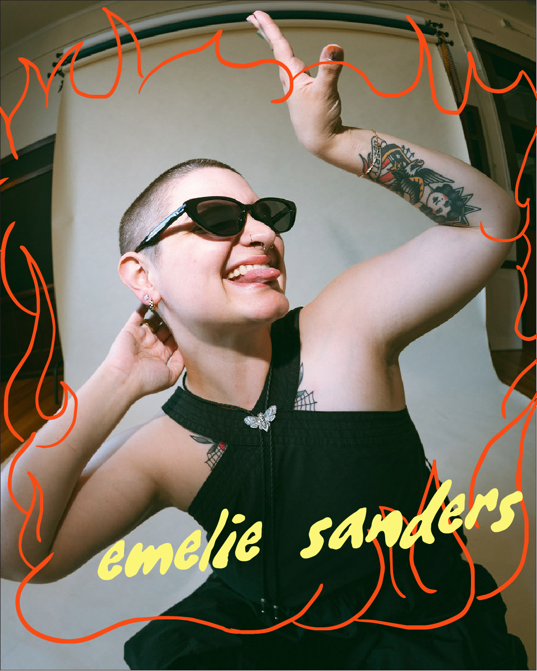 girl wearing dark sunglasses and dark dress squatting down and sticking tongue out all sassy like with red flames border and word emelie sanders at bottom