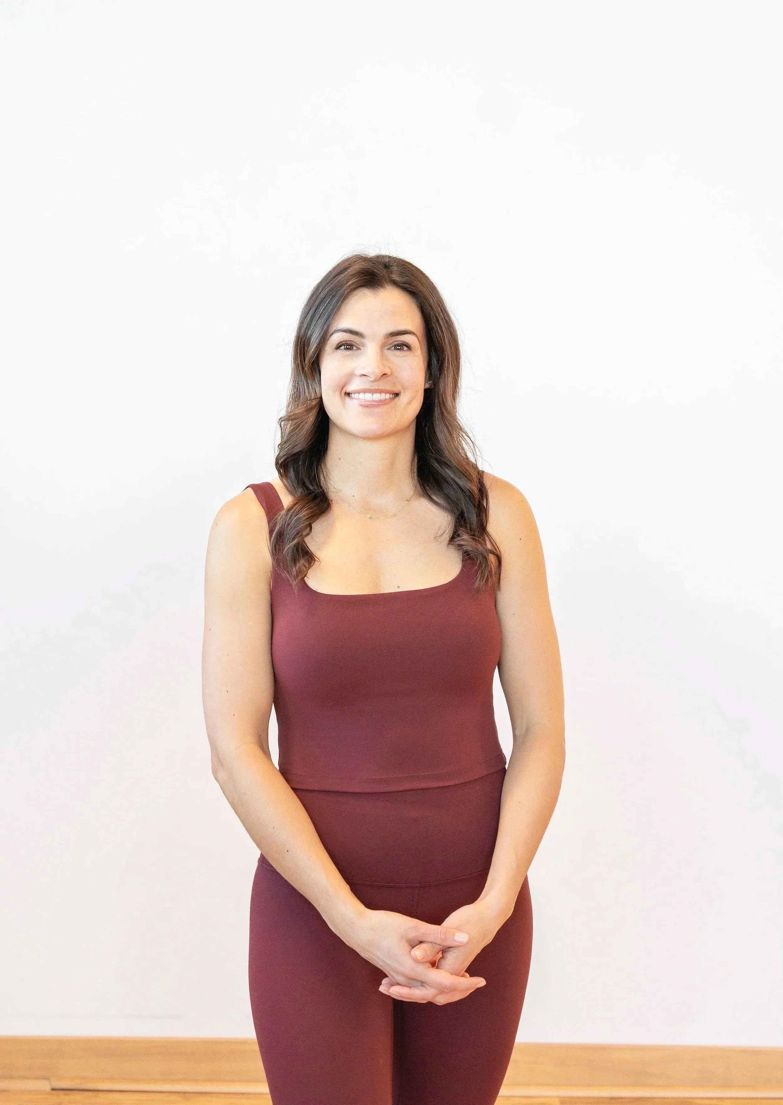 Woman with brunette hair standing against a plain colored background