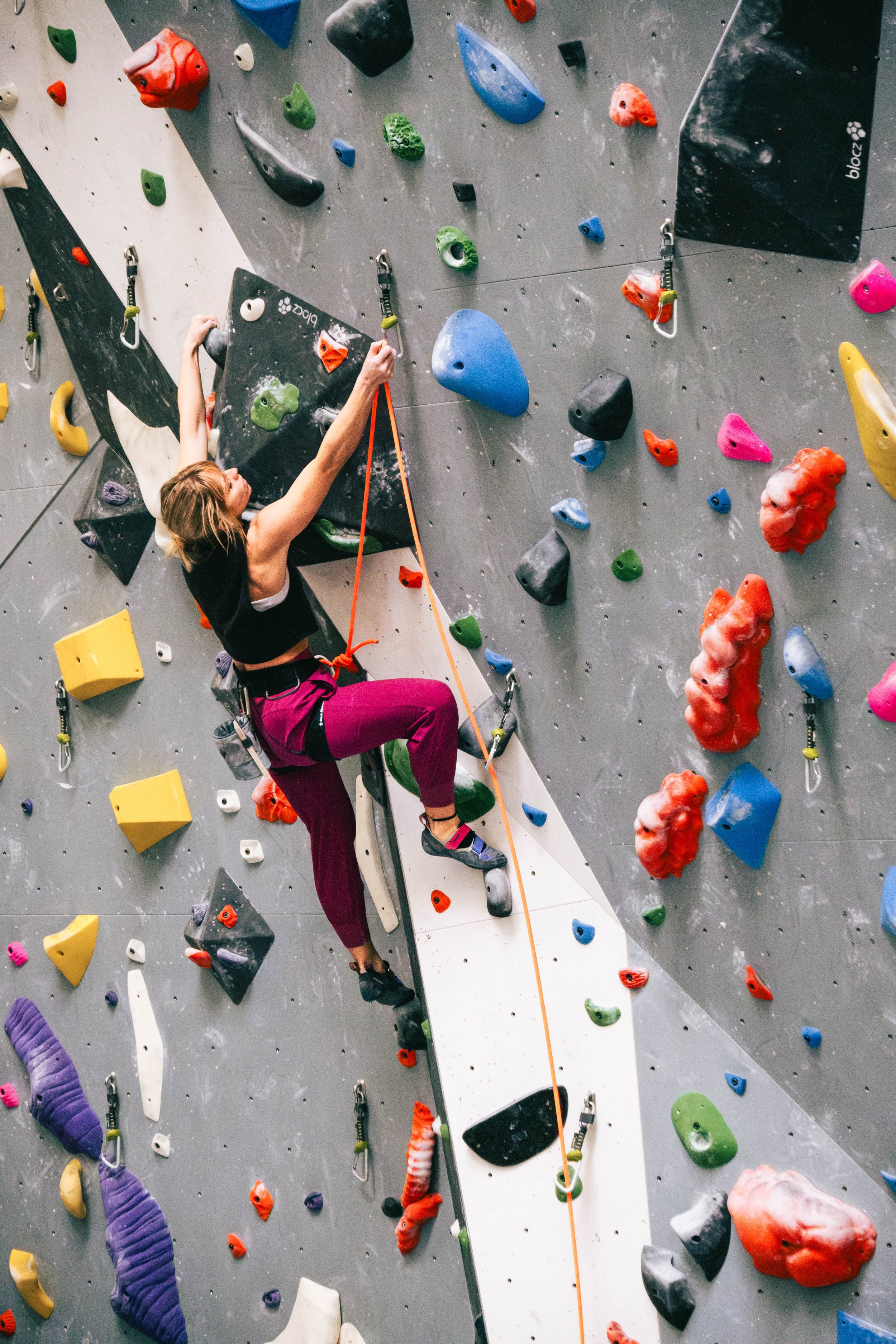 A girl is lead climbing and clipping herself into the next quickdraw