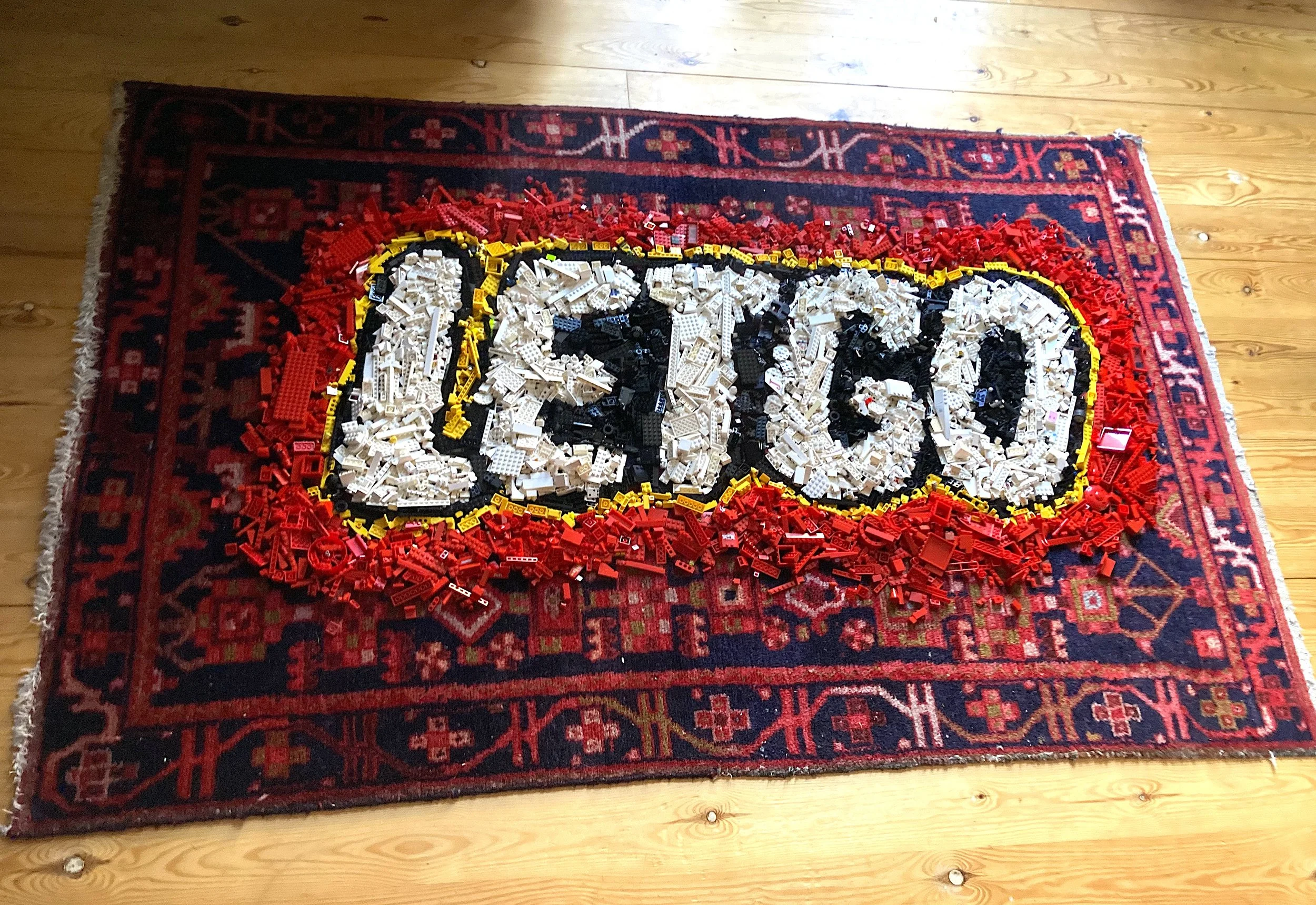 'Let go' (2025) toy bricks, vintage rug. Shown installed in artist's home.