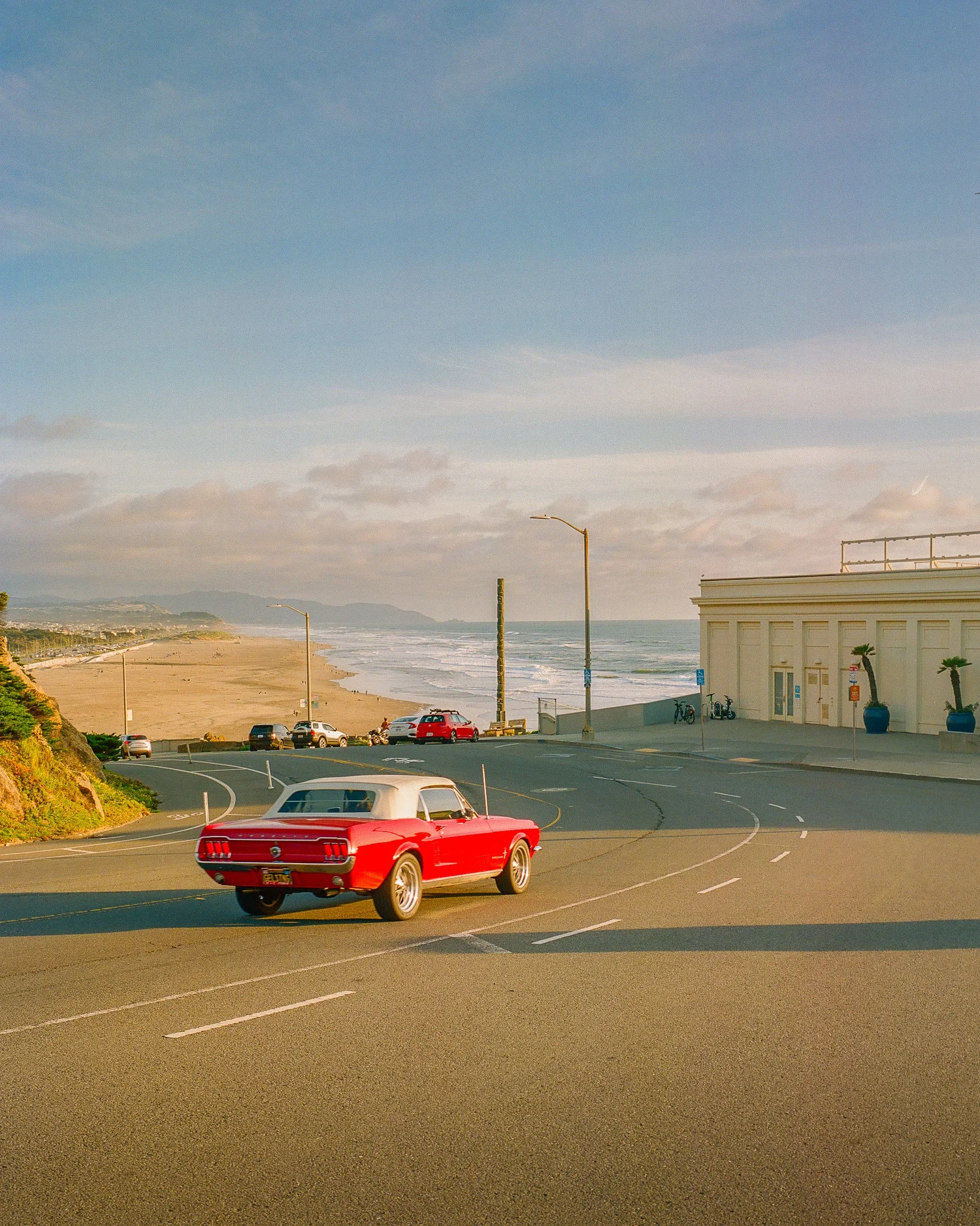 Red classic car on a coastal road overlooking the beach