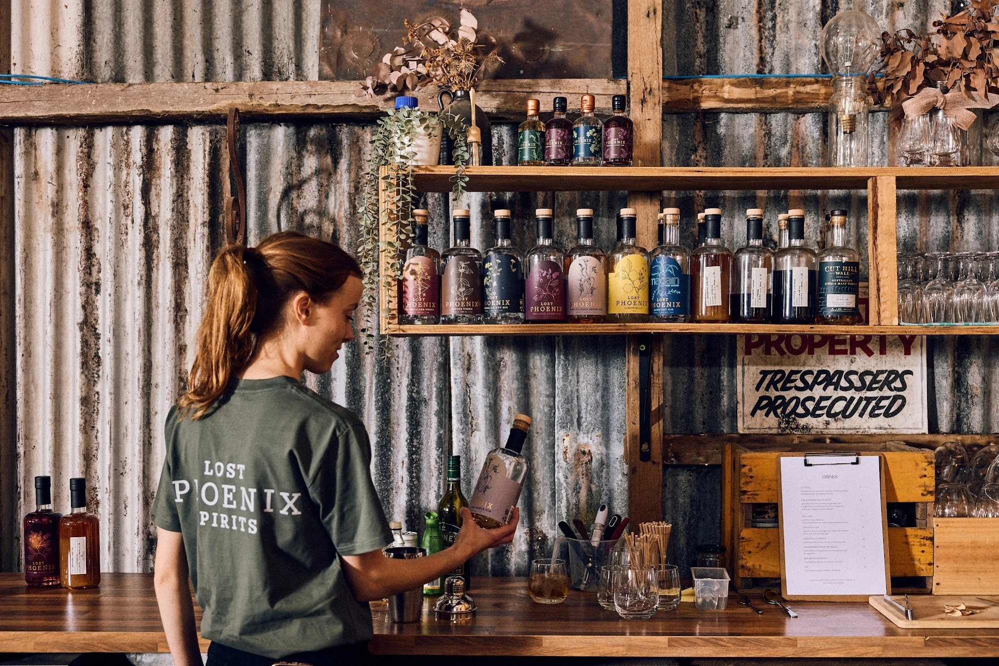 Team member reaching for a bottle from the Lost Phoenix Spirits shelves at The Spirit Door
