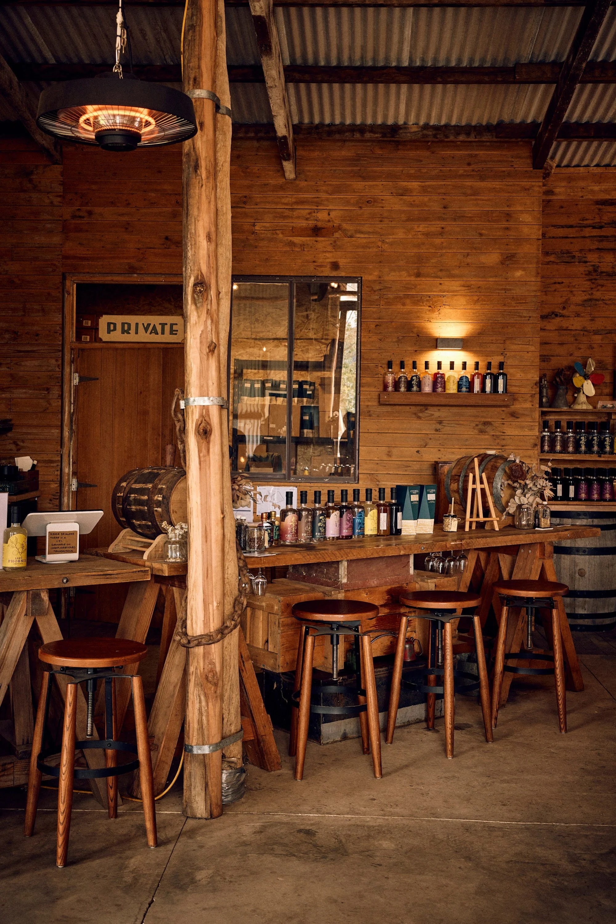 Tasting bar at The Spirit Door with barrels, bar stools and bottles of Lost Phoenix Spirits
