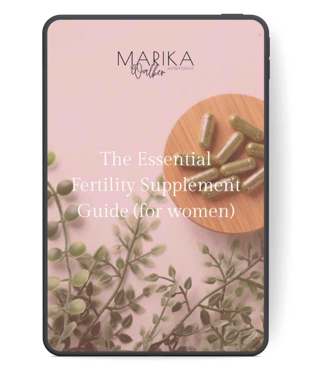 Cover of a guide titled "The Essential Fertility Supplement Guide (for women)" by Marika Walker Nutritionist, featuring a pink background, green capsules on a wooden plate, and some green leaves.