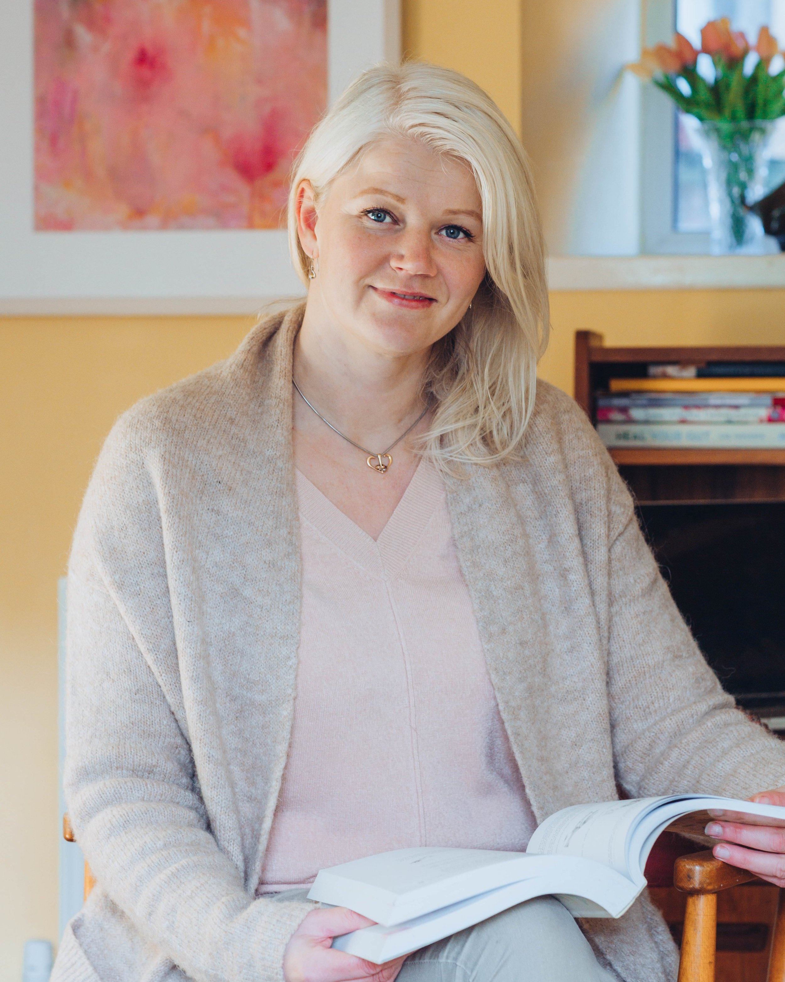 marika walker, fertility nutritionist, posing with an open book on her lap.