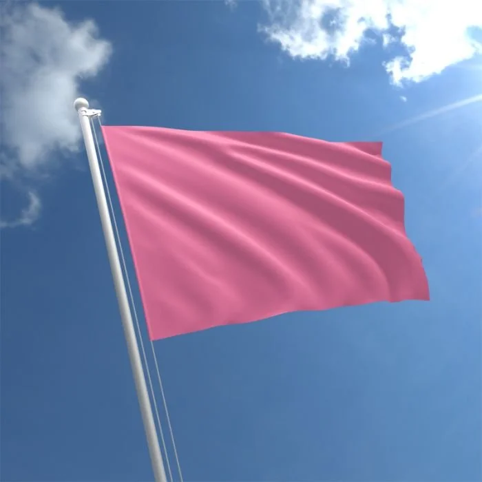 Pink flag waving on a flagpole against a clear blue sky with clouds.