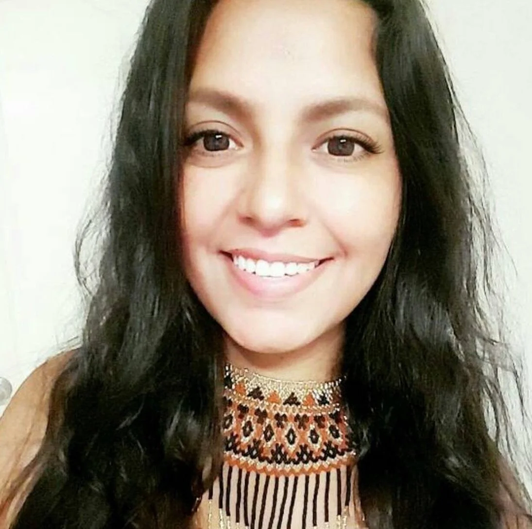Close-up of Raquel Saenz smiling, wearing a colorful patterned top.