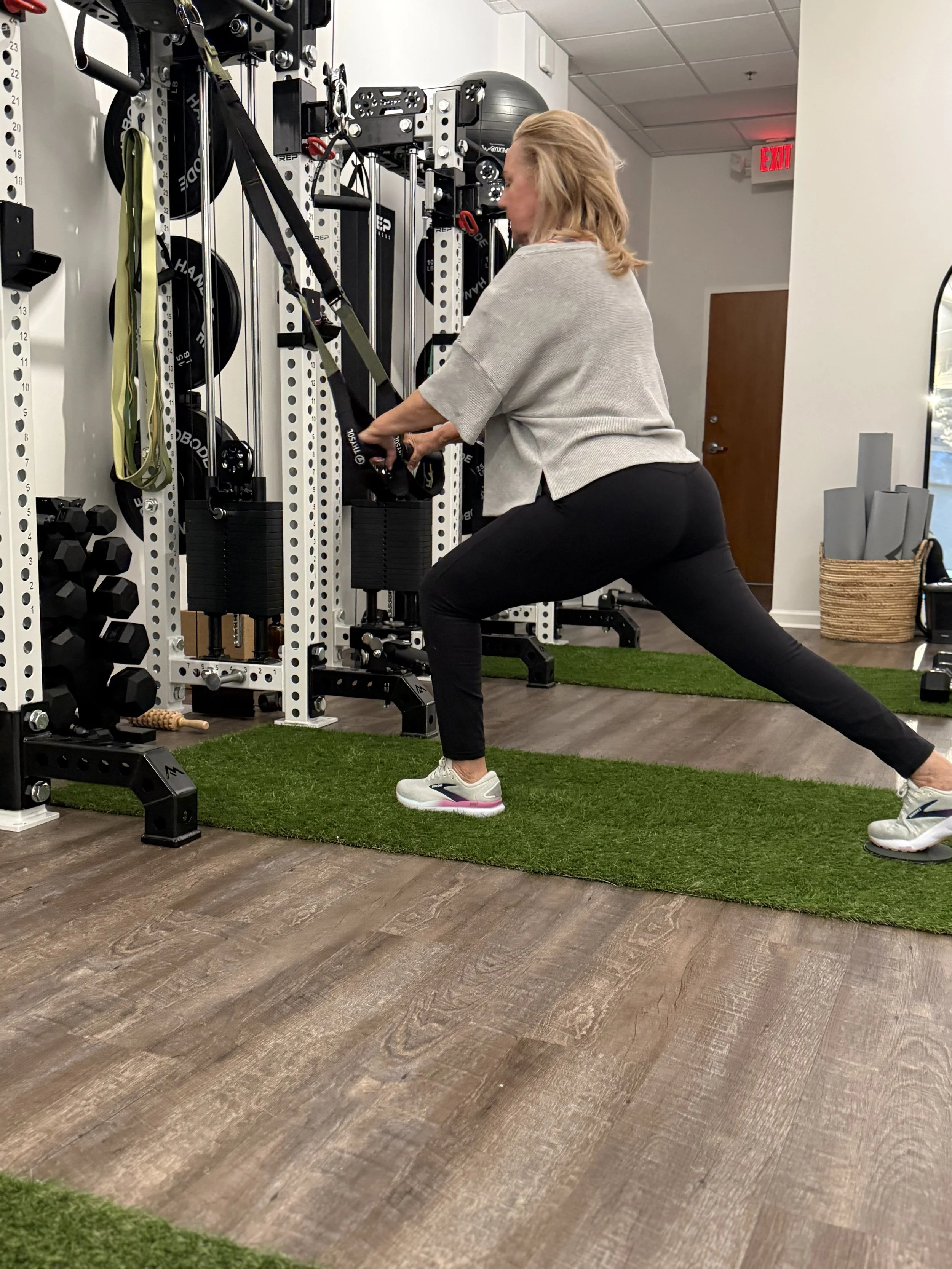 Silhouette of a girl jumping in front of a large wave at a beach during sunset.