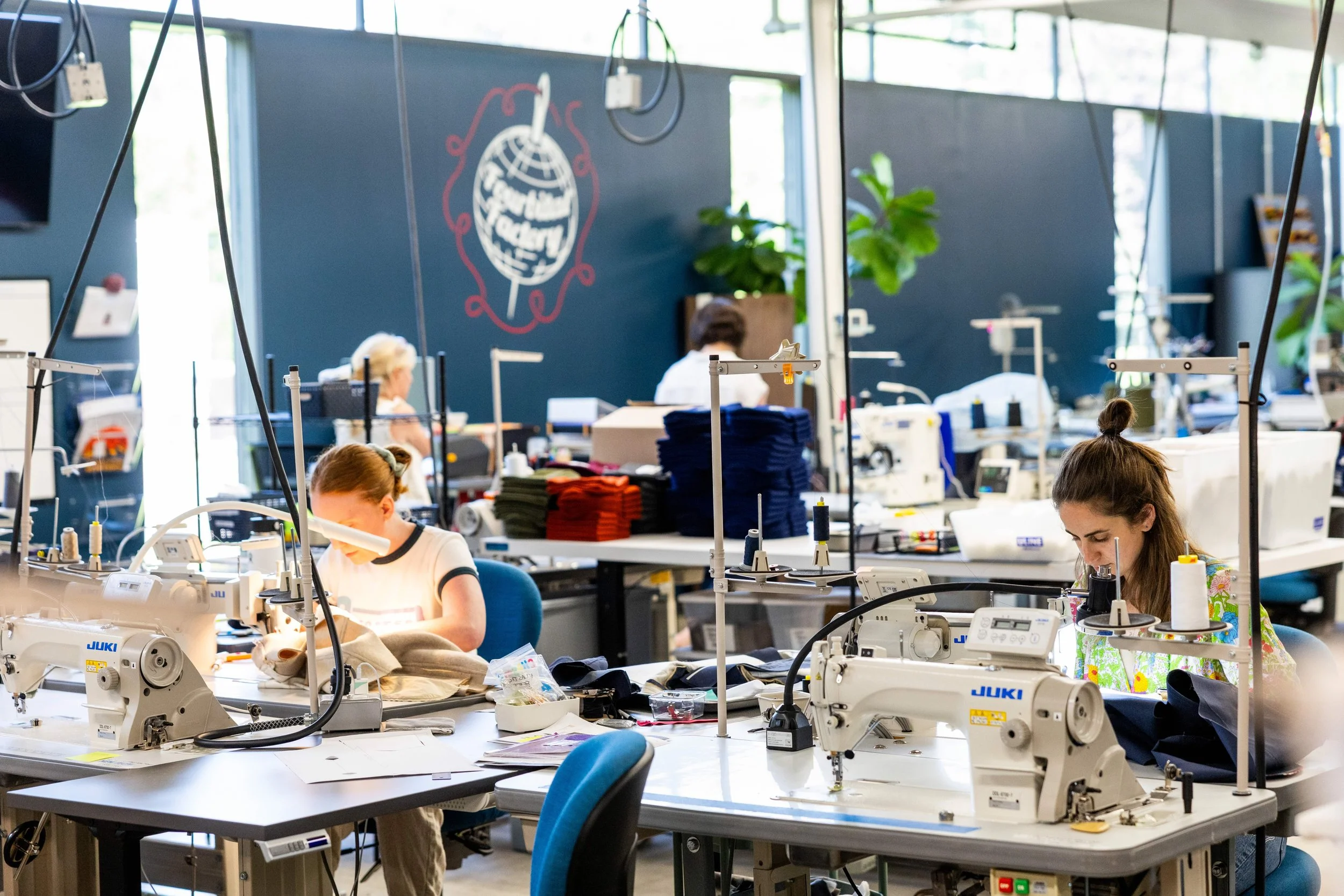 photo of two women at fourbital factory sewing beanies