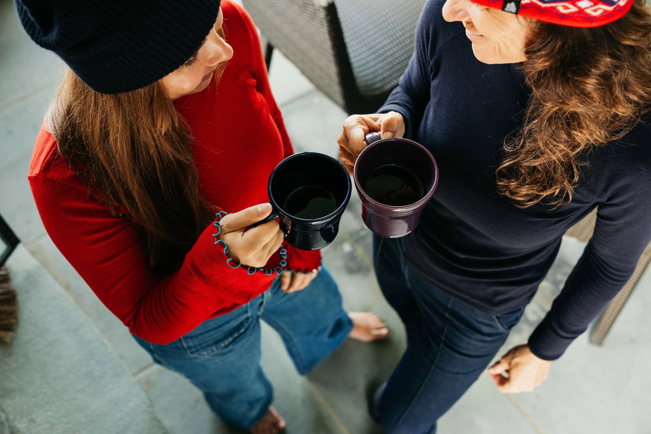 two women wearing fourbital factory beanies holding coffee cups and smiling