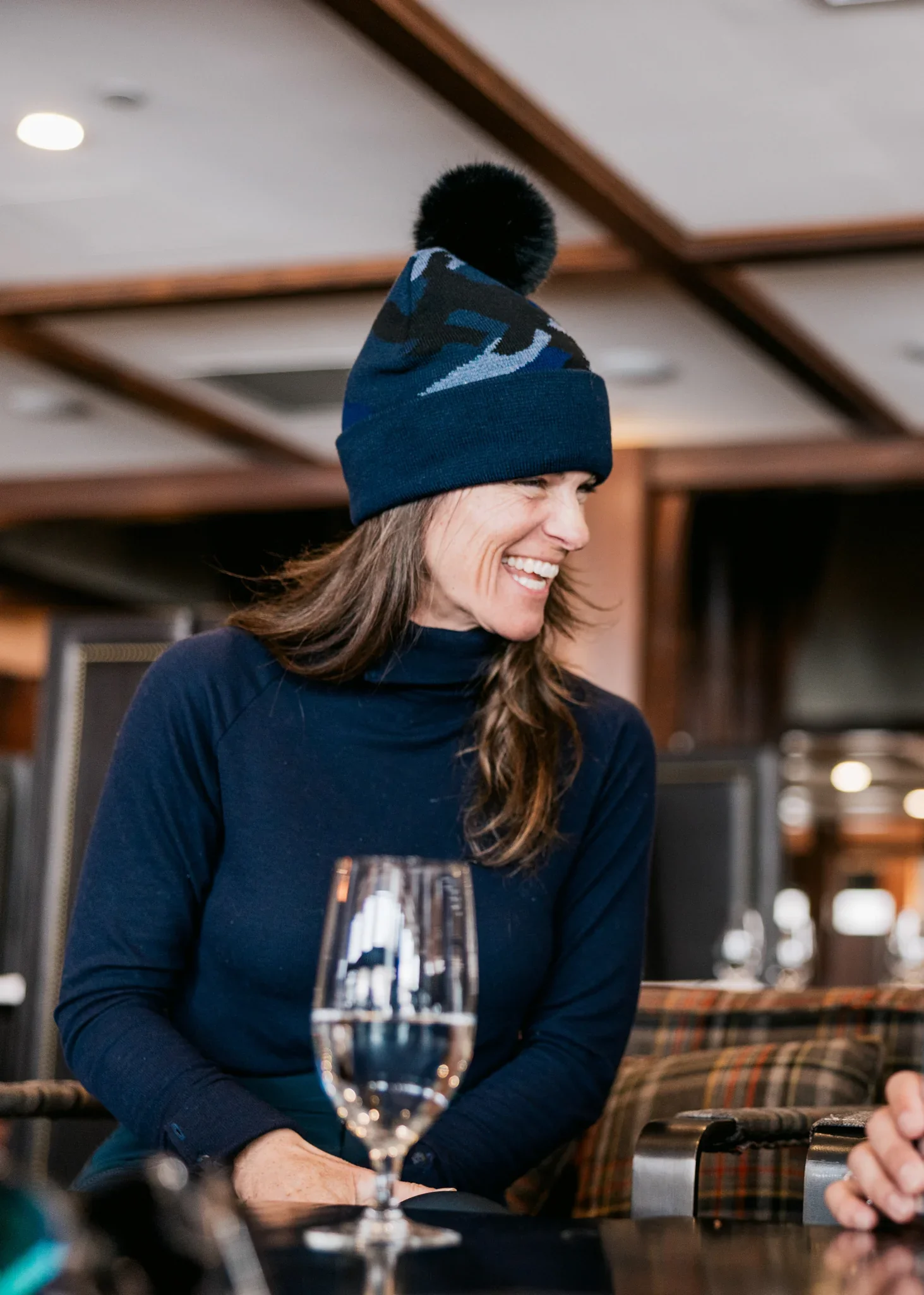 woman wearing a cuffed pom beanie while smiling
