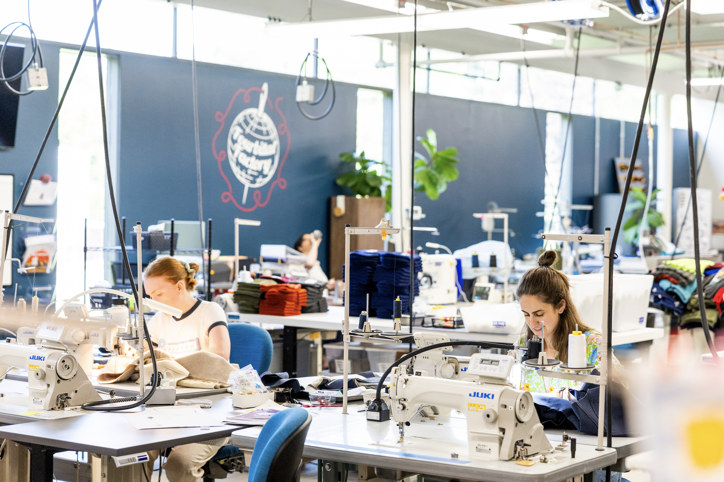 two women sewists at fourbital factory sitting behind their sewing machines