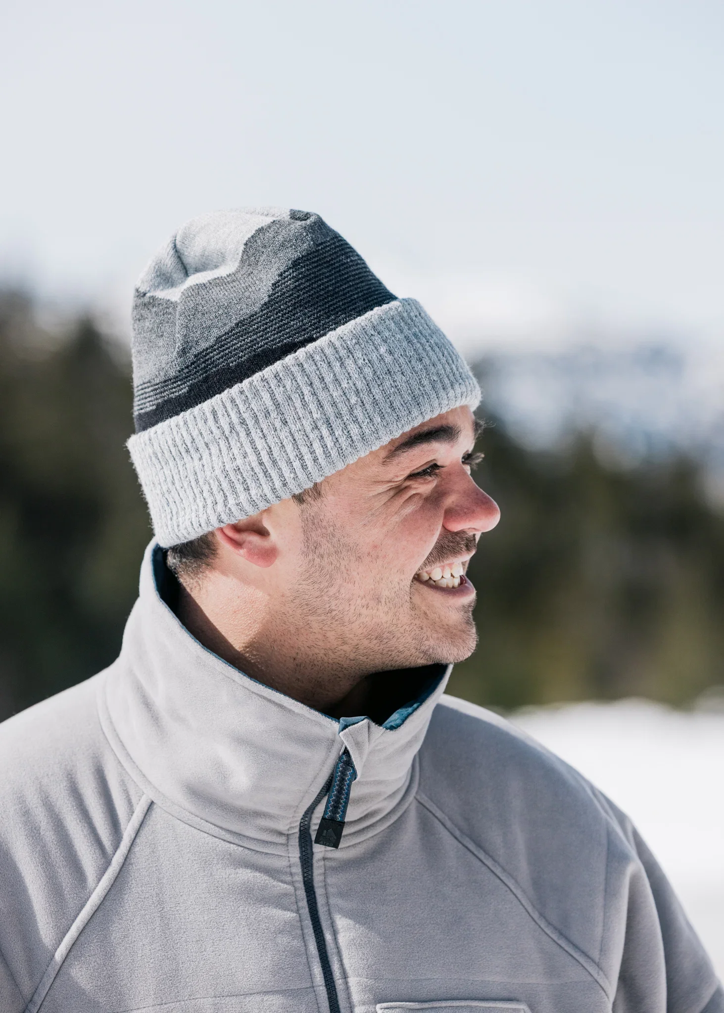 man wearing a grey and black cuffed beanie while smiling