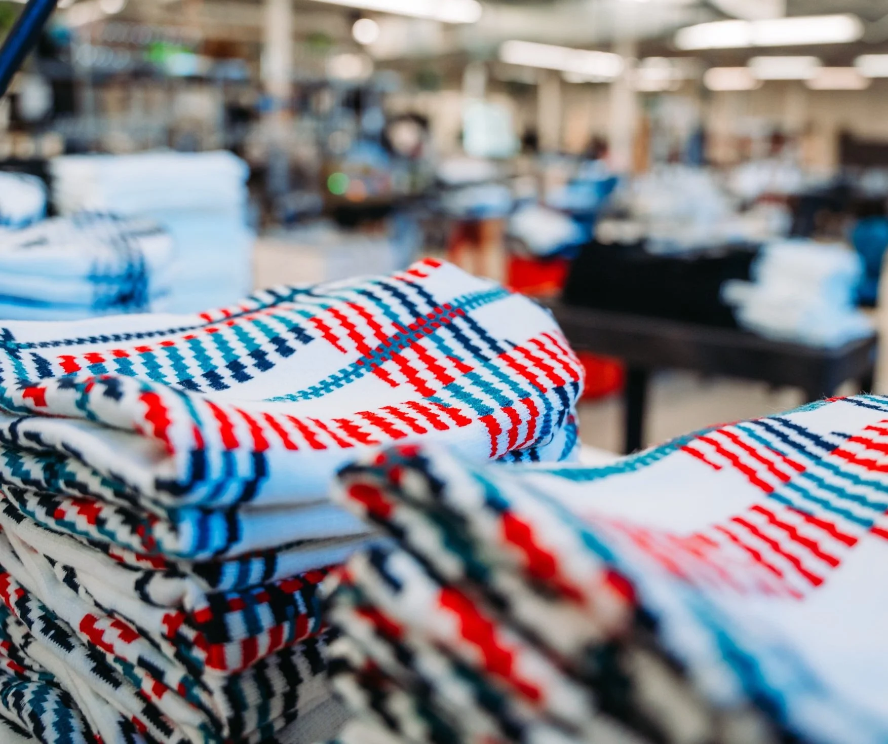 a stack of red white and blue jacquard beanies being prepped for shipping at fourbital factory in burlington vermont