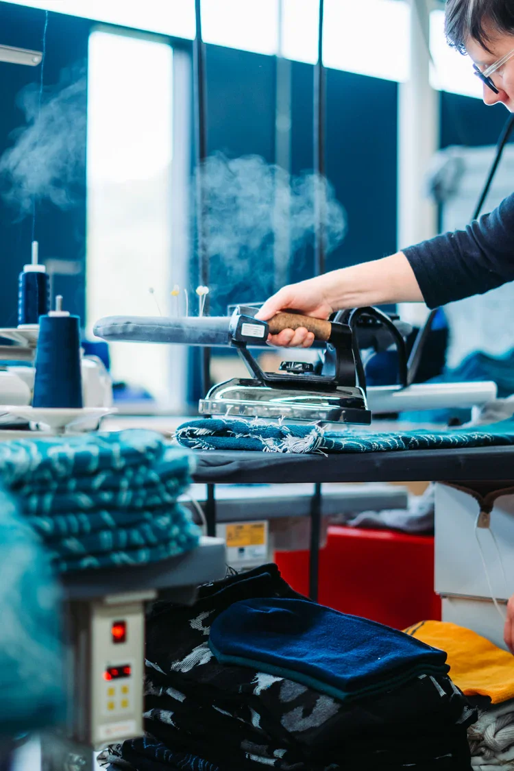 worker ironing beanies at fourbital factory