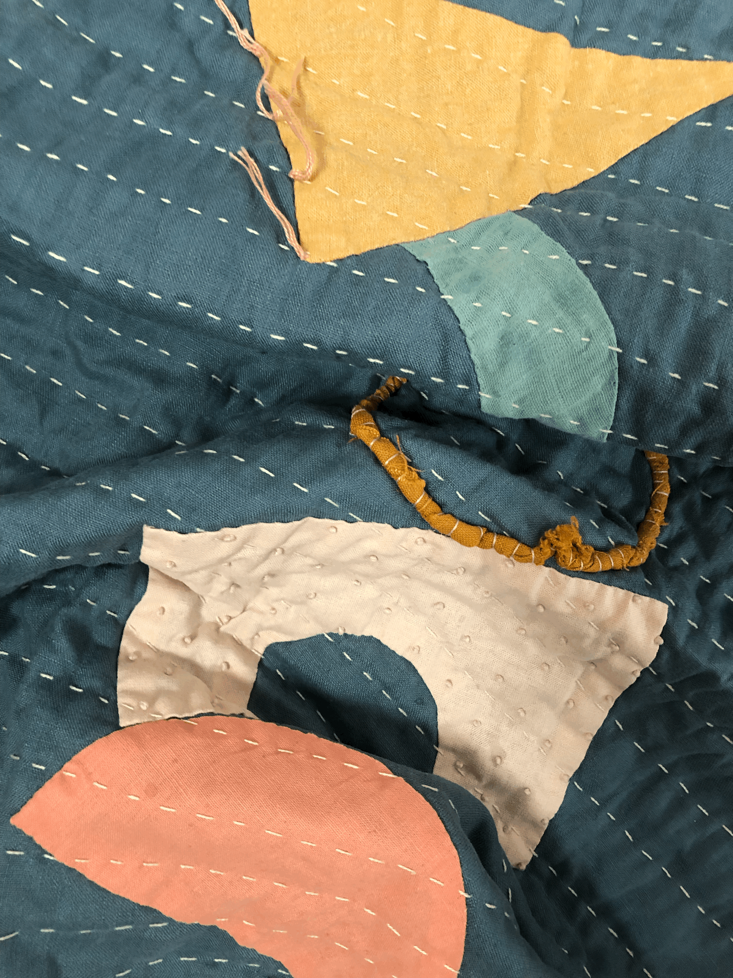 Close up of hand quilted stitches and appliqué shapes.