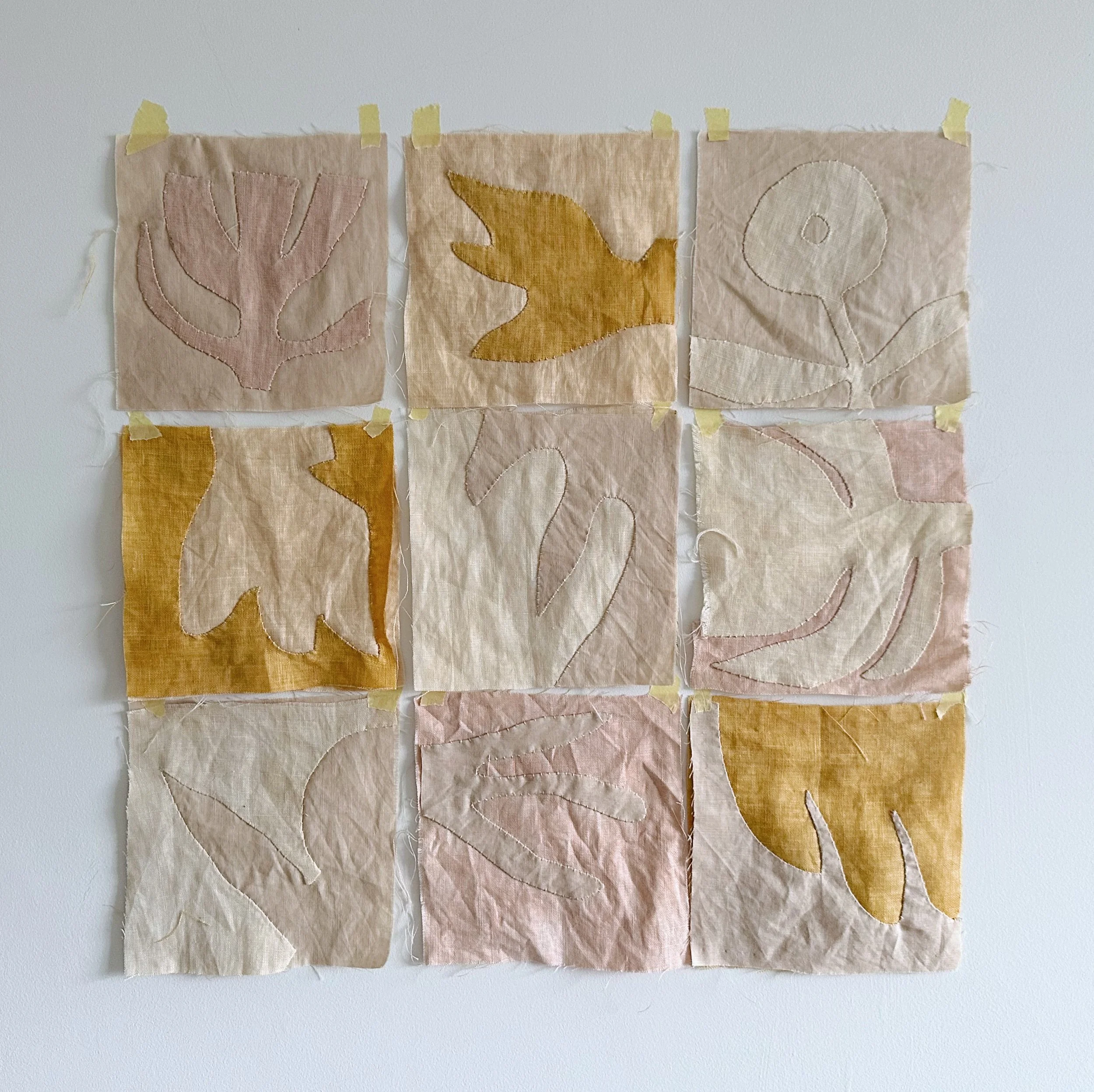 9 abstract floral reverse applique blocks from Rebekah Johnston's tutorial, taped to a wall.