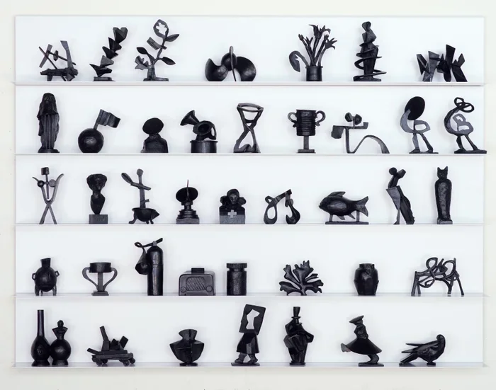 William Kentridge small black sculptures displayed on 5 shelves.