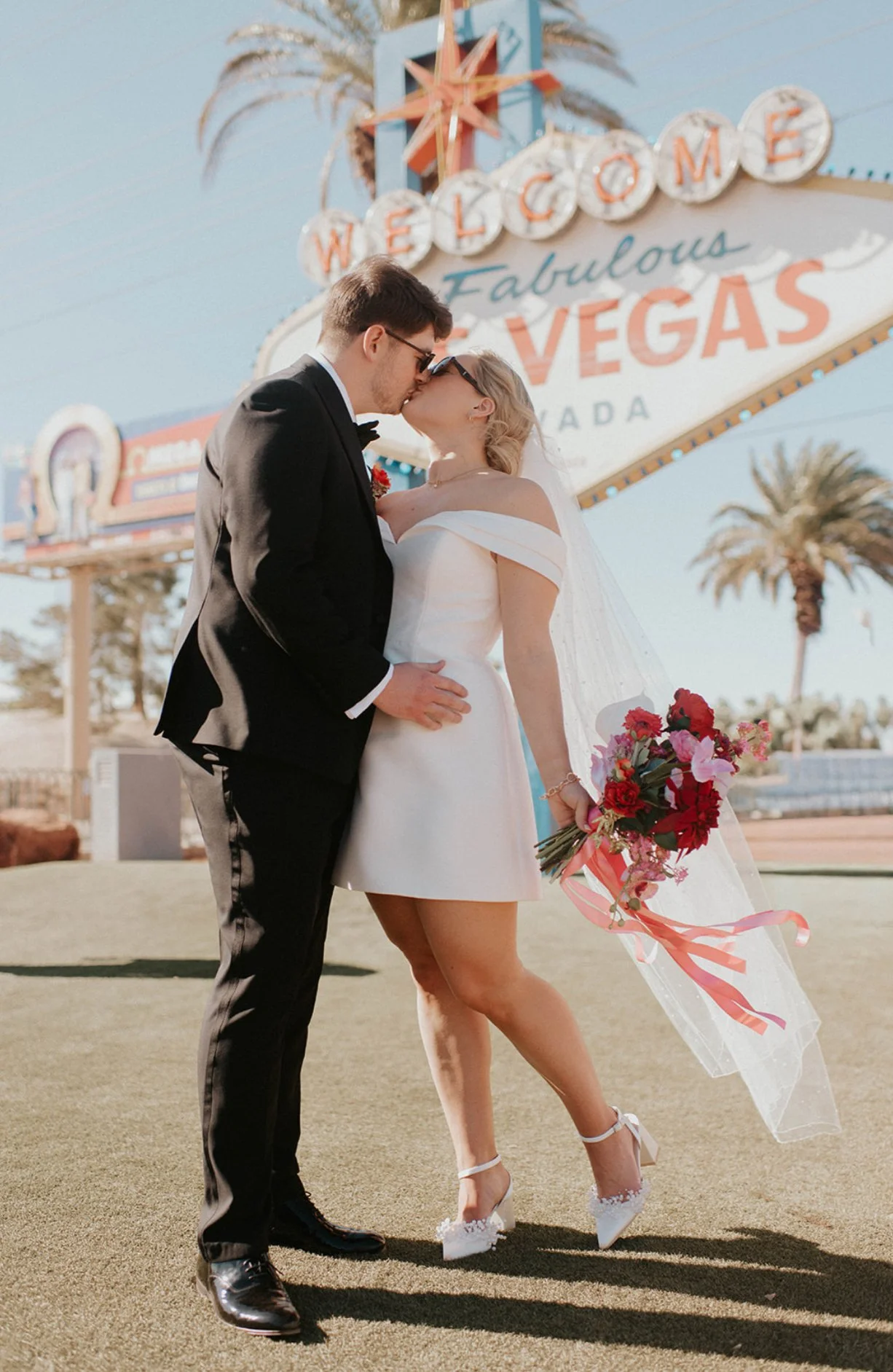 Betty and Joe sharing a kiss beneath the Welcome to Fabulous Las Vegas sign on their wedding day at Sure Thing Chapel.