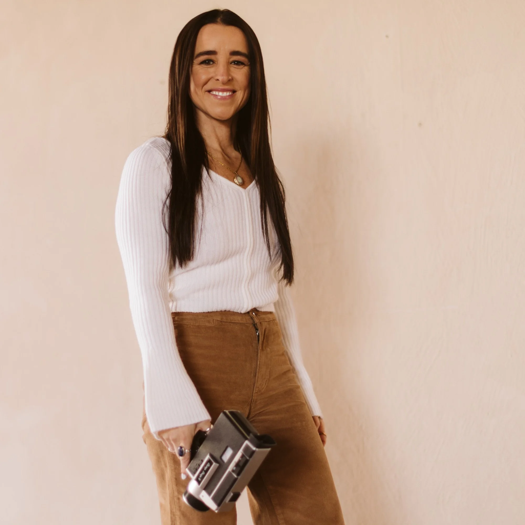 Kaylee LaMoine smiling and holding a vintage film camera