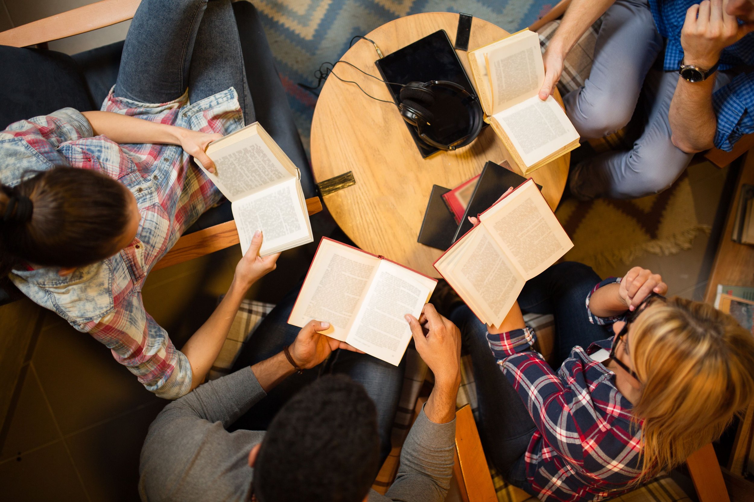 diverse-group-of-friends-discussing-a-book-in-library--583816330-59cd08c76f53ba001111922a.jpg