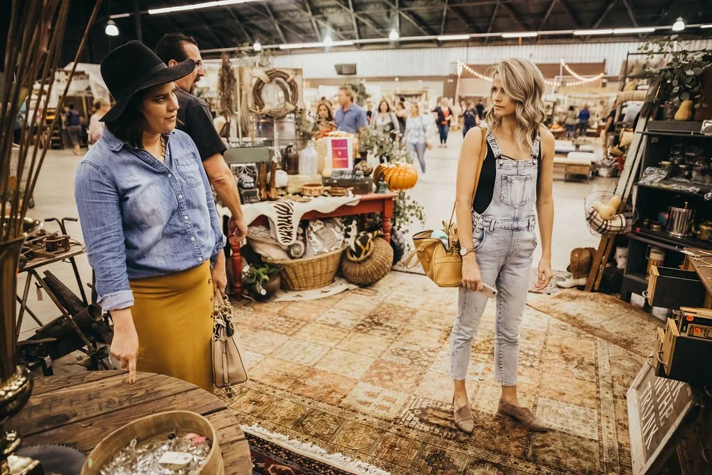 People looking at a rustic wooden table at a vintage market. 