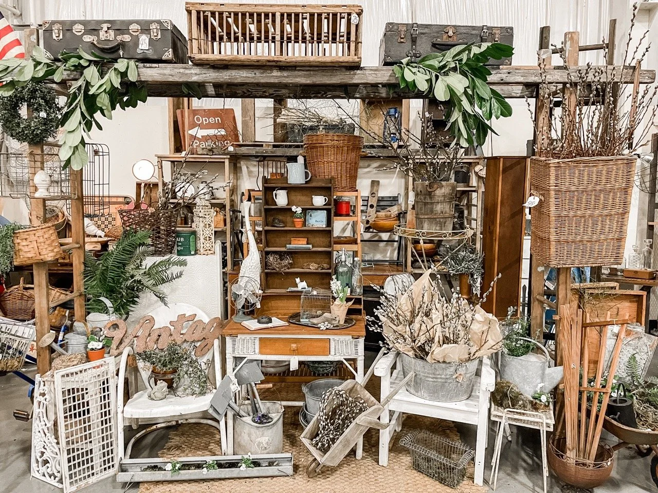 A display of vintage table and chairs, baskets, suitcases and other decorative items. 