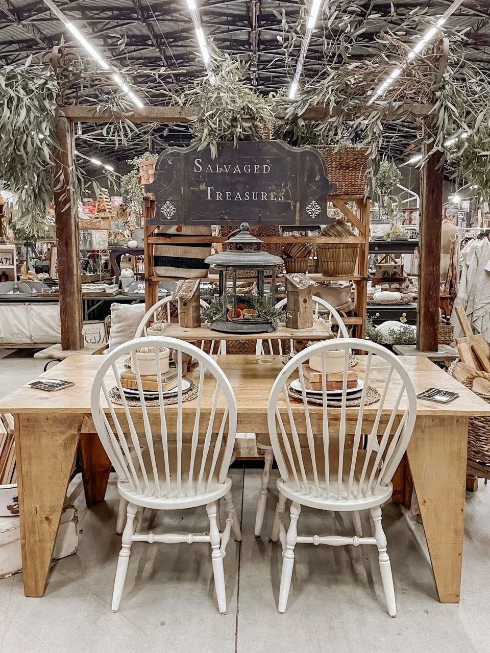 A wooden sign says "Salvaged Treasures" hanging over a rustic kitchen table. 