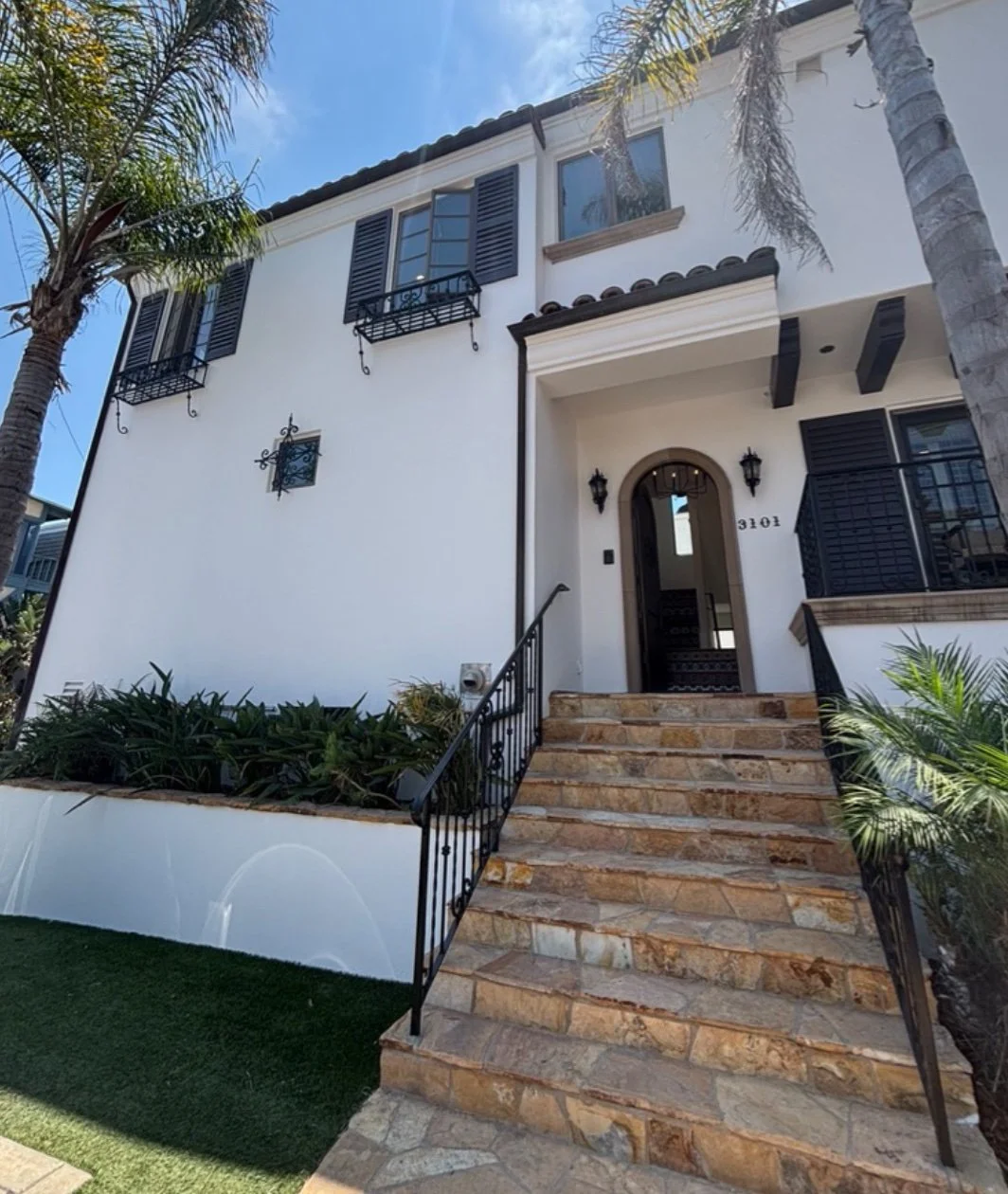 mediterranean home with white walls, palm trees, paved walkway, spanish accents, and greenery located in Manhattan Beach