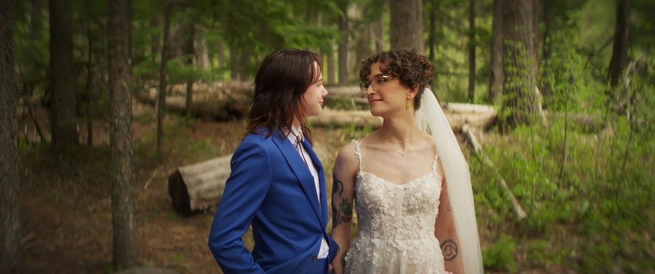 Clover and Jill among tall trees on their wedding day