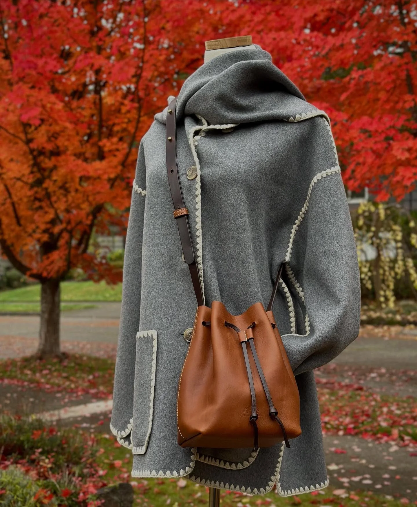 Our red maples make a nice backdrop to a new Bucket Bag design. 🍁

This one is crafted using whiskey Minerva Box with Buttero for the strap that is stained dark brown.  Saddle-stitched with cream waxed thread.
The inside bottom is lined with calf. 
