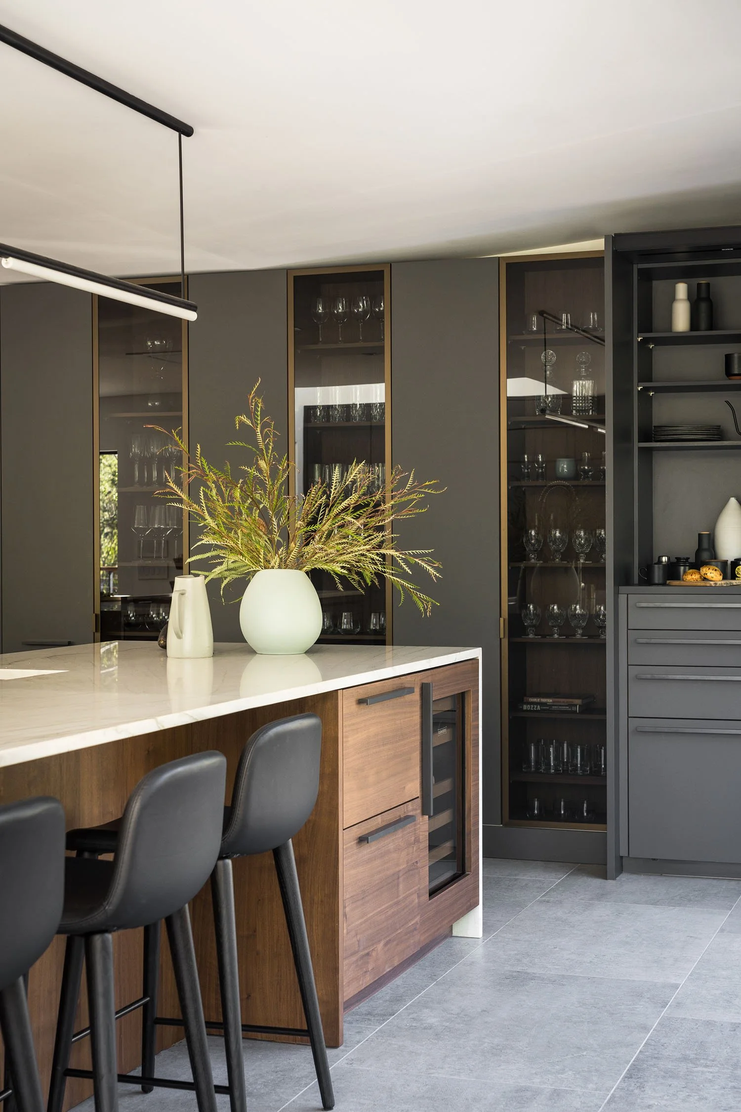 Modern kitchen in the Orinda house renovation with walnut island, marble countertop, black leather barstools, and glass-front cabinetry in the East Bay, San Francisco