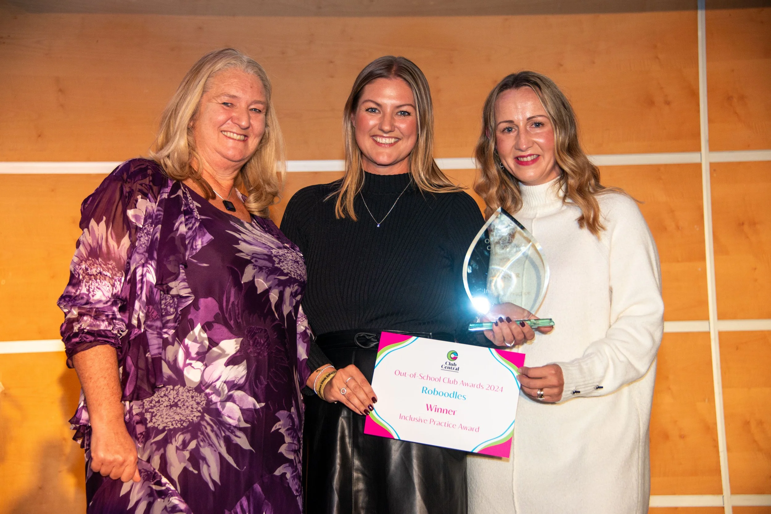 Three smiling females with an award and a certificate