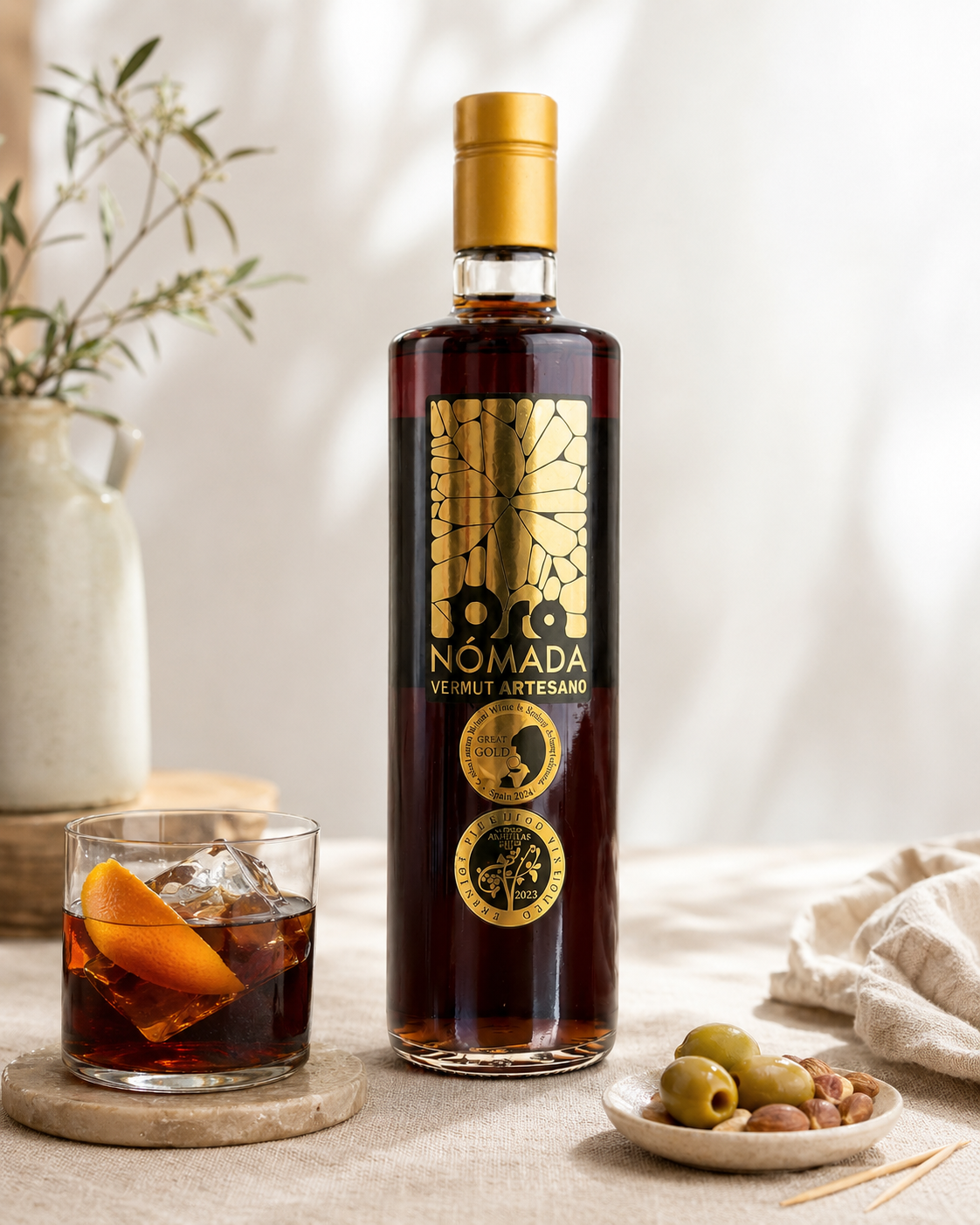Oro Nómada Original servido con hielo y naranja junto a una botella de 750 ml