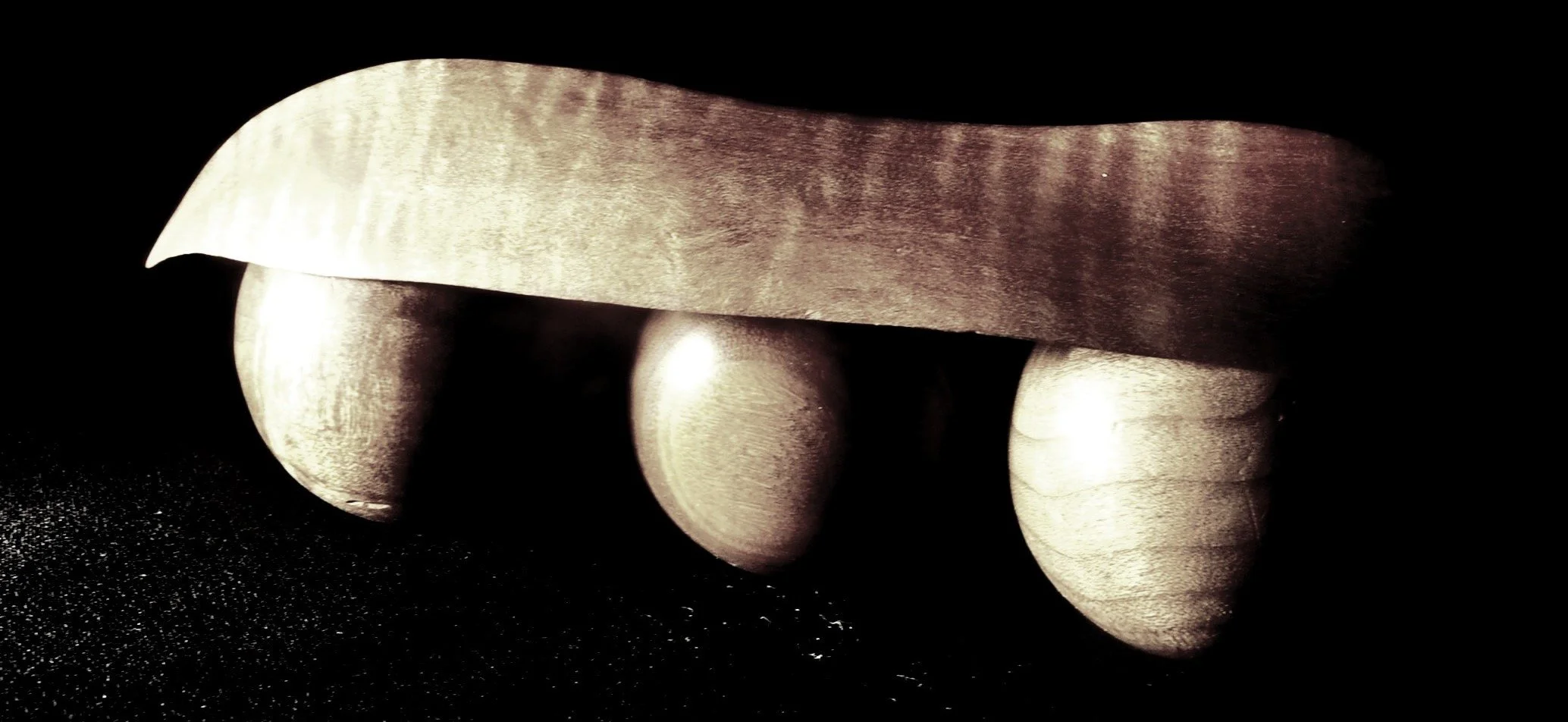 Close-up of fingers holding a metallic knife with a dark background.