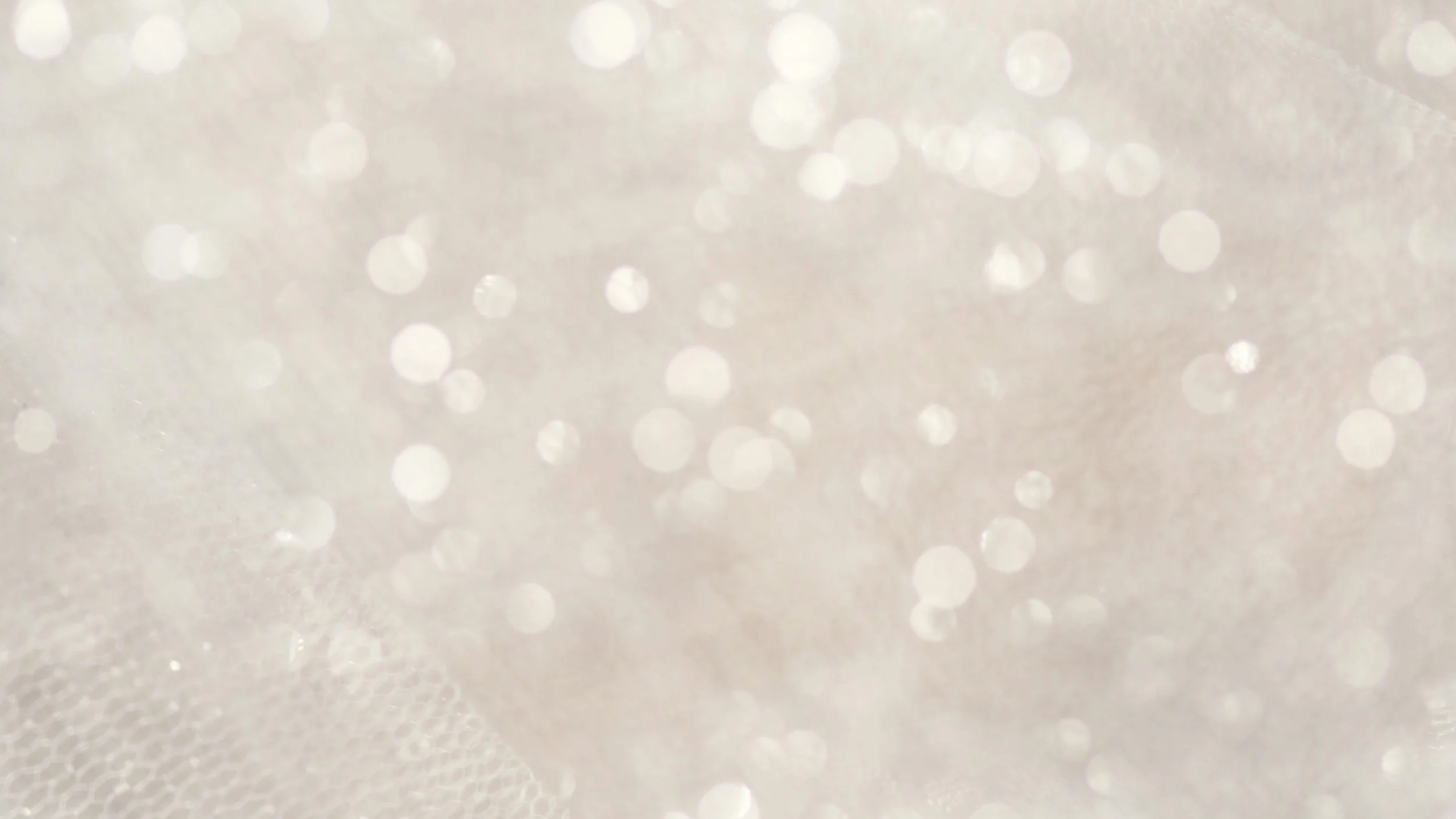 Close-up of a white surface with numerous small, shiny, out-of-focus light reflections or bokeh effects.
