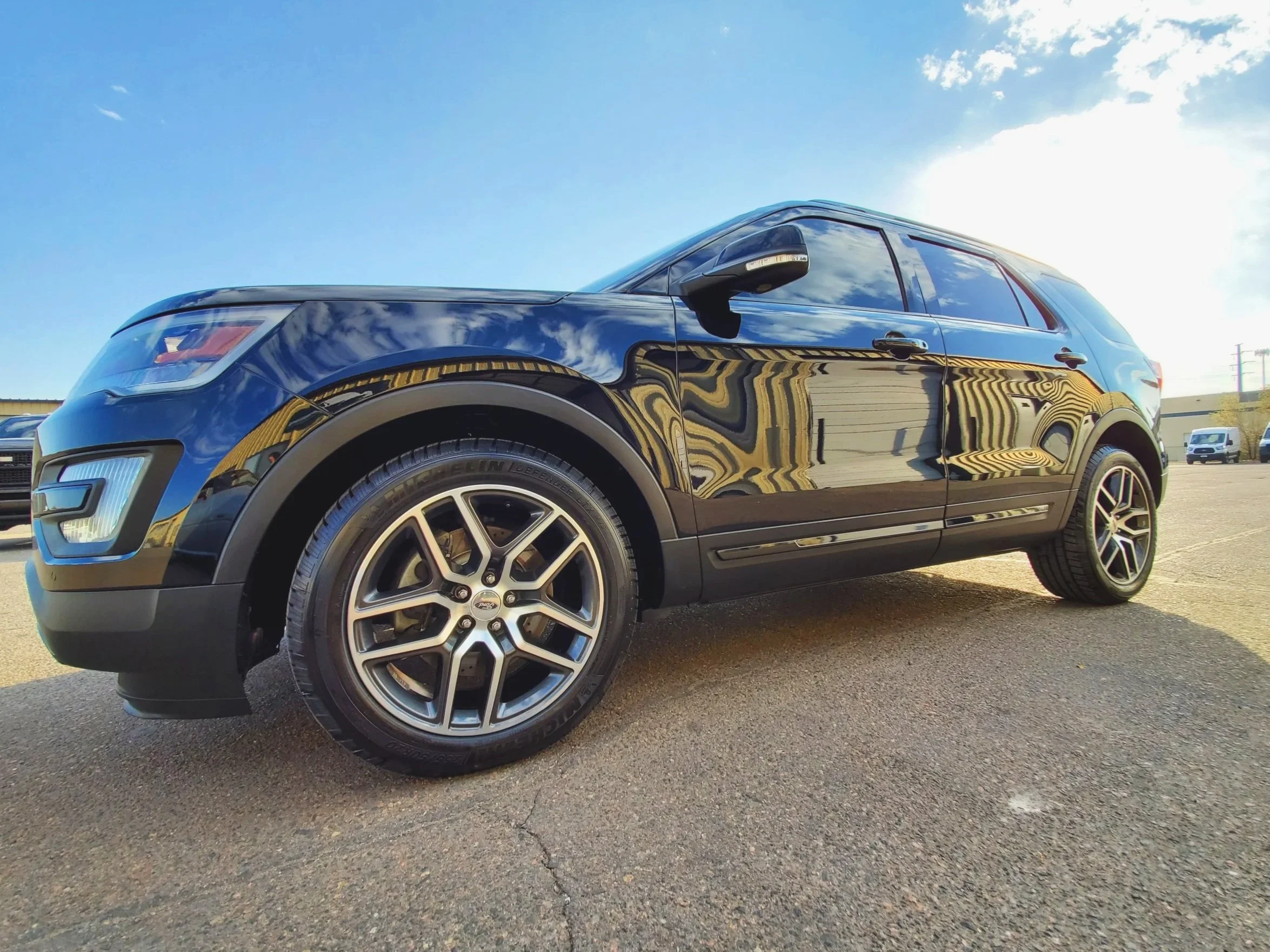 Black SUV parked outdoors with a clear sky and other vehicles in the background.