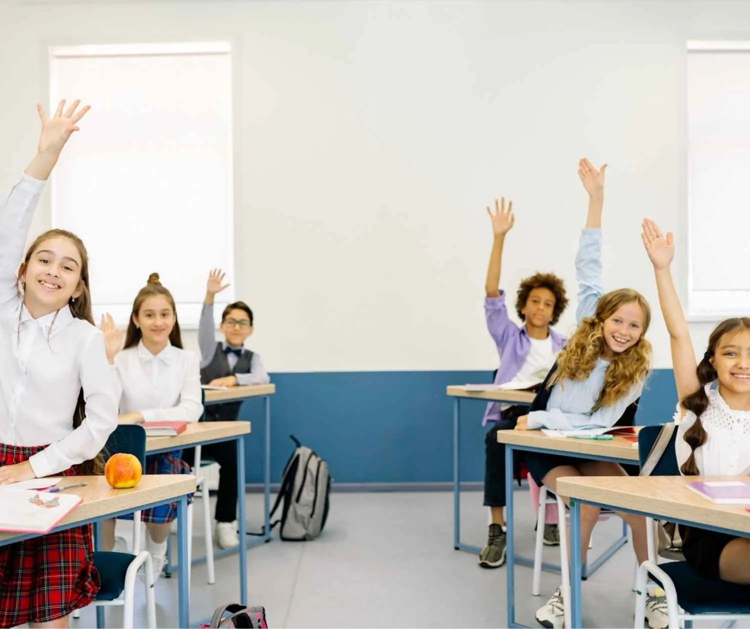 Young students raising their hands in a classroom