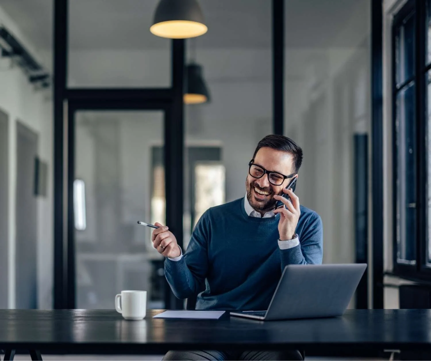 Man smiling while talking on the phone at work