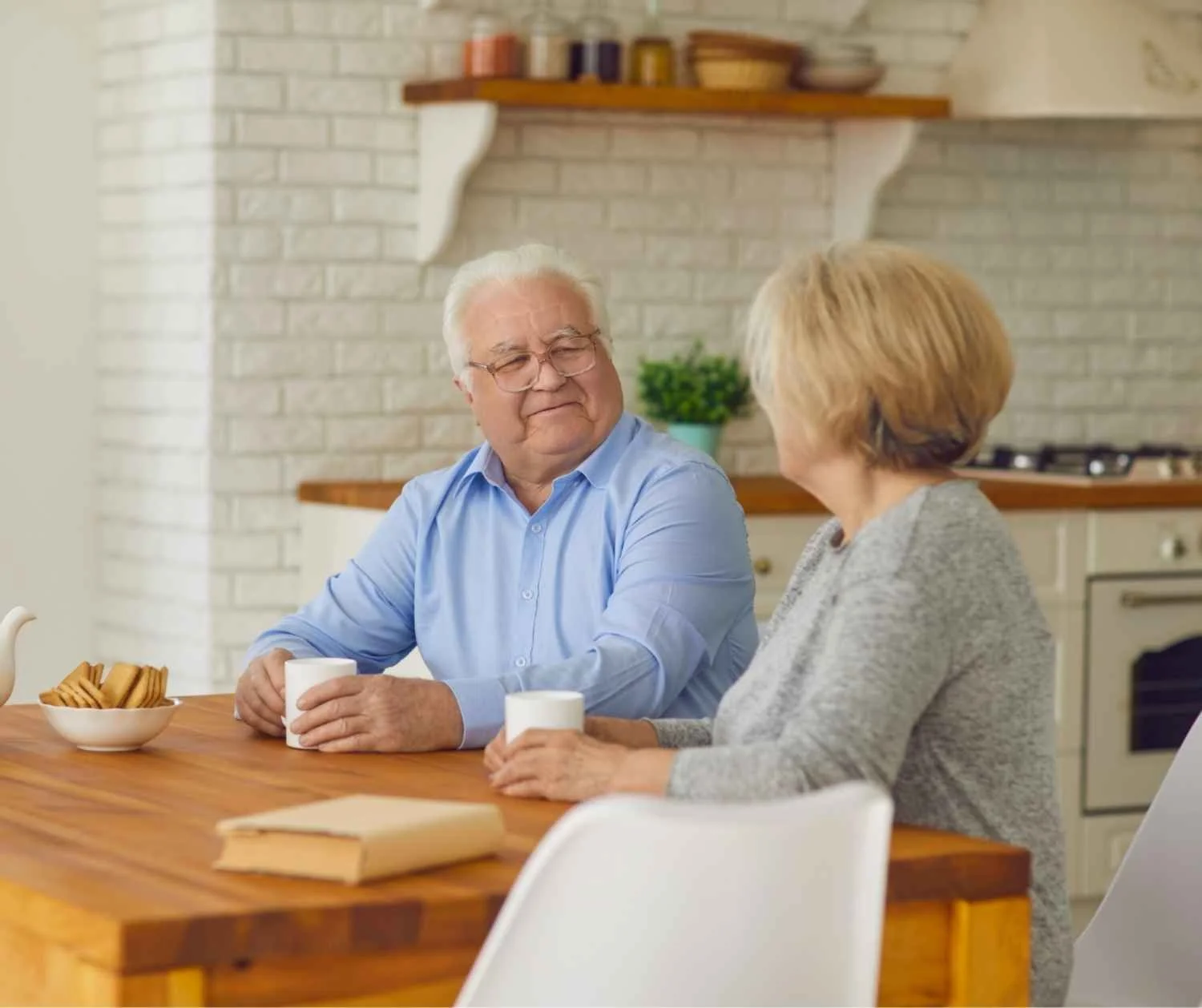 Older couple talking together at their kitchen table.
