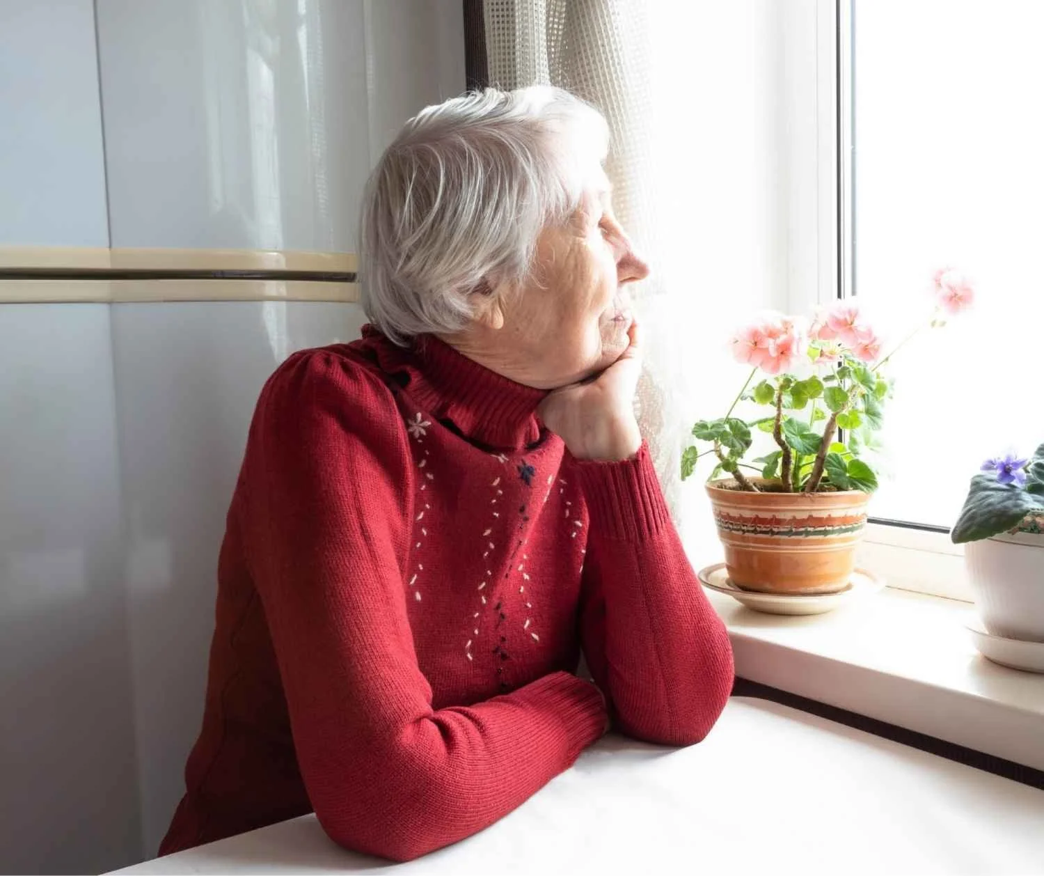 Older woman looking out the window in the kitchen