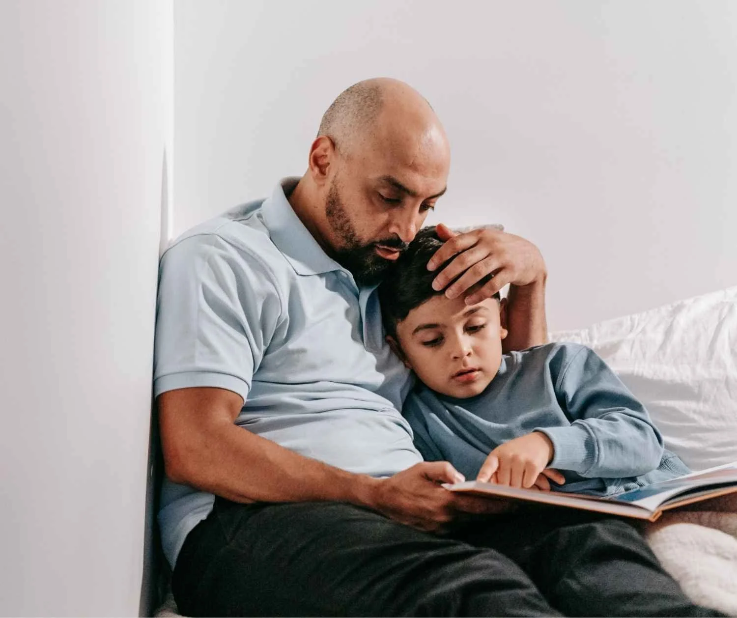 Father and son reading a picture book together on the sofa