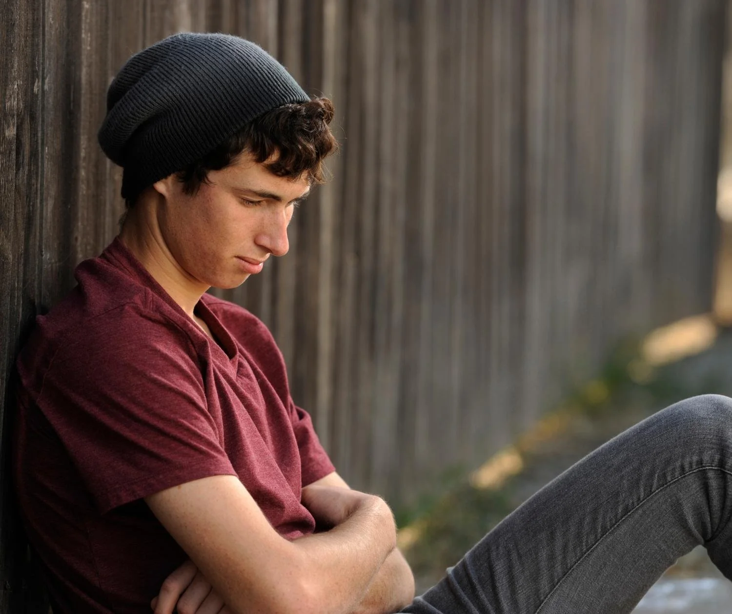 A teen boy sitting alone looking down
