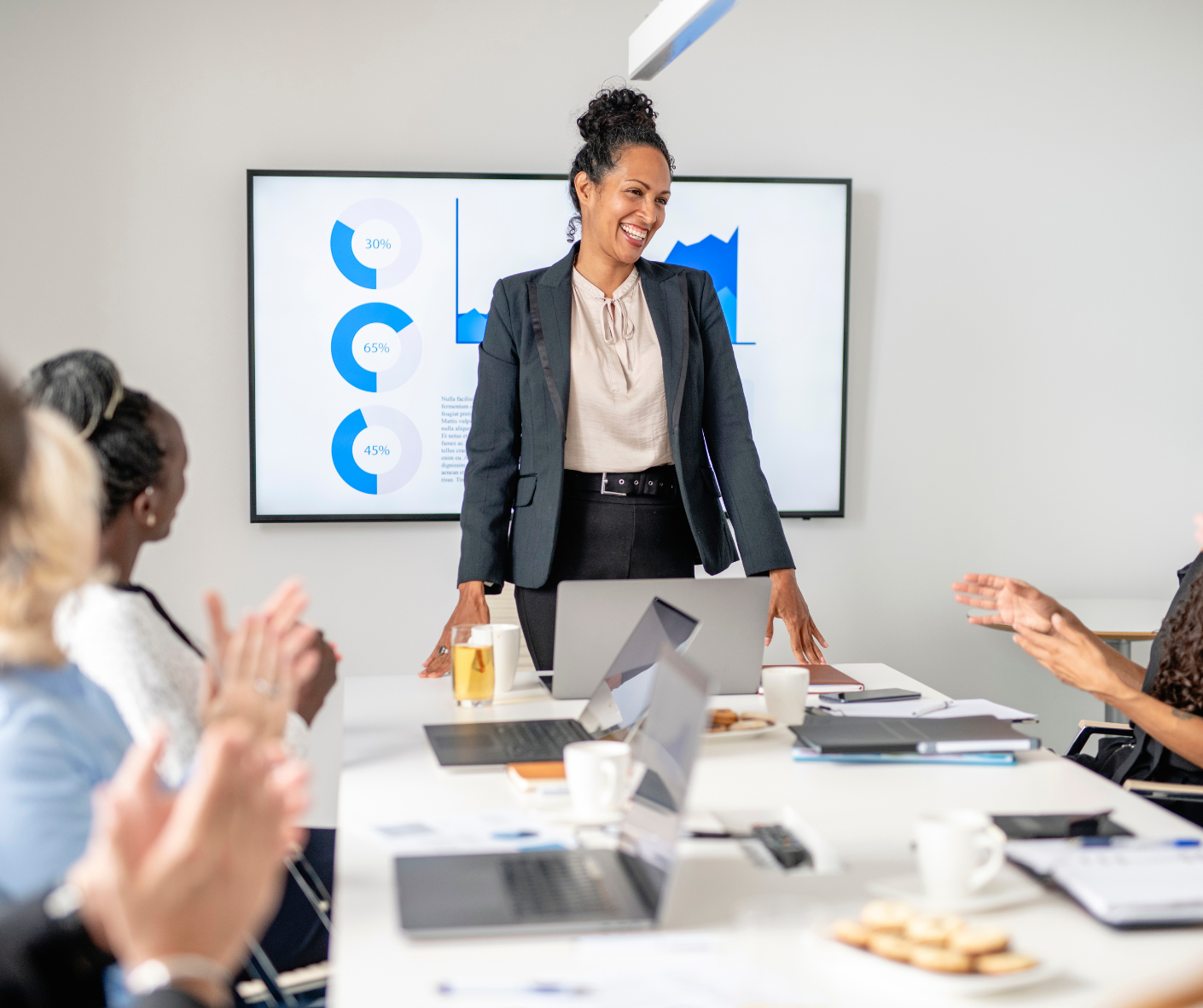 Leader presenting to her team in front of a screen during a meeting