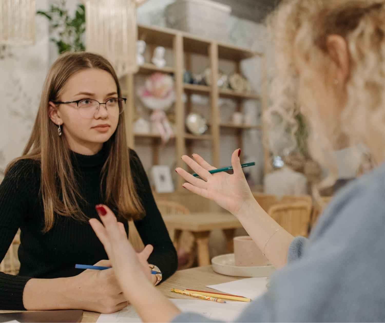 Woman rehearsing a short talk in a meeting room while a colleague listens and gives feedback