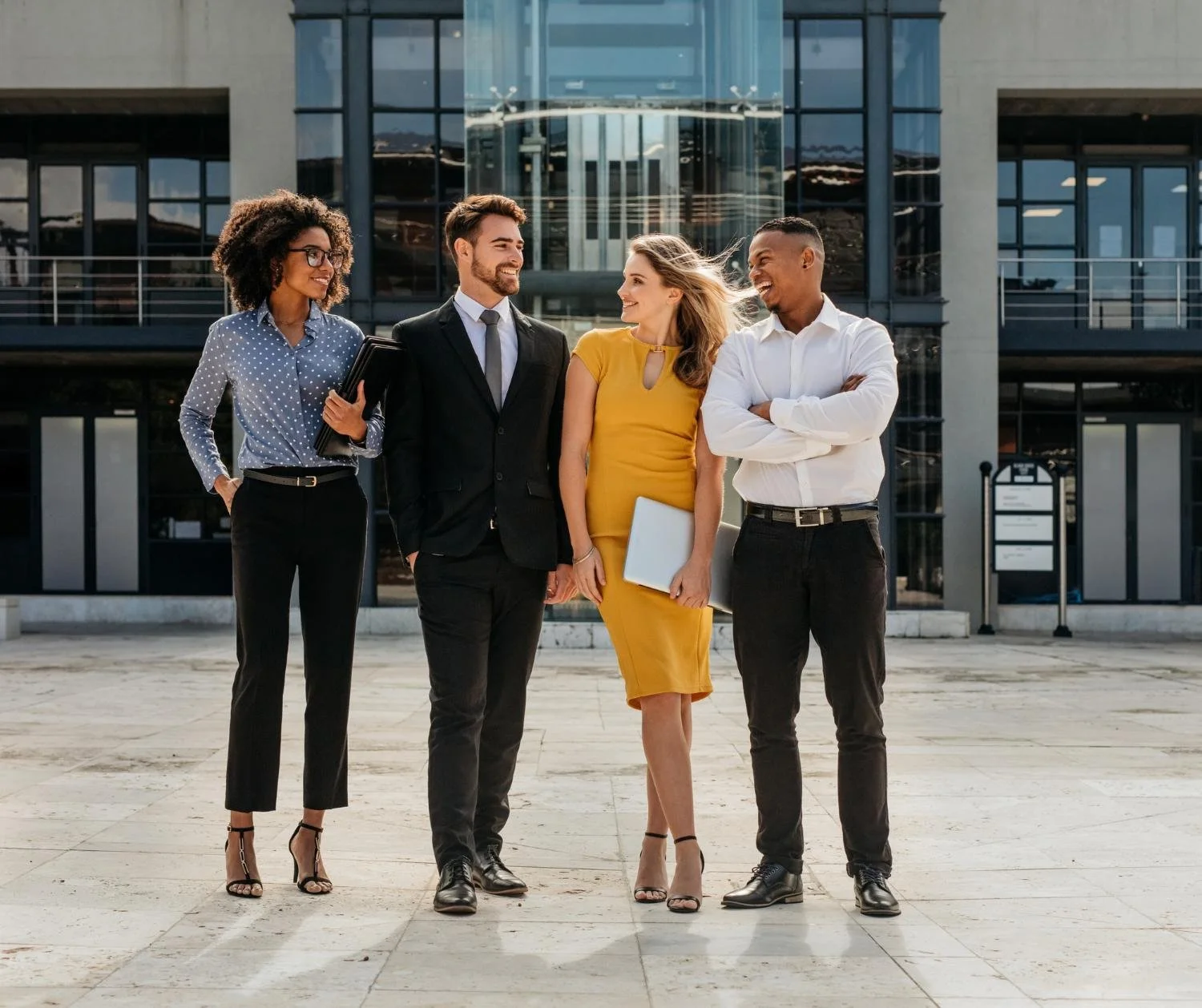 Four coworkers walking and talking outside an office building.