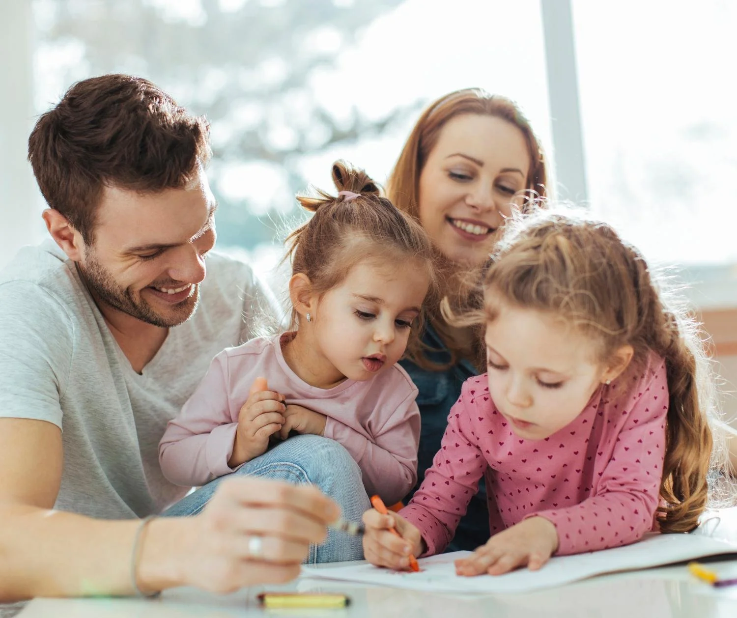 Parents drawing with their two young daughters at home
