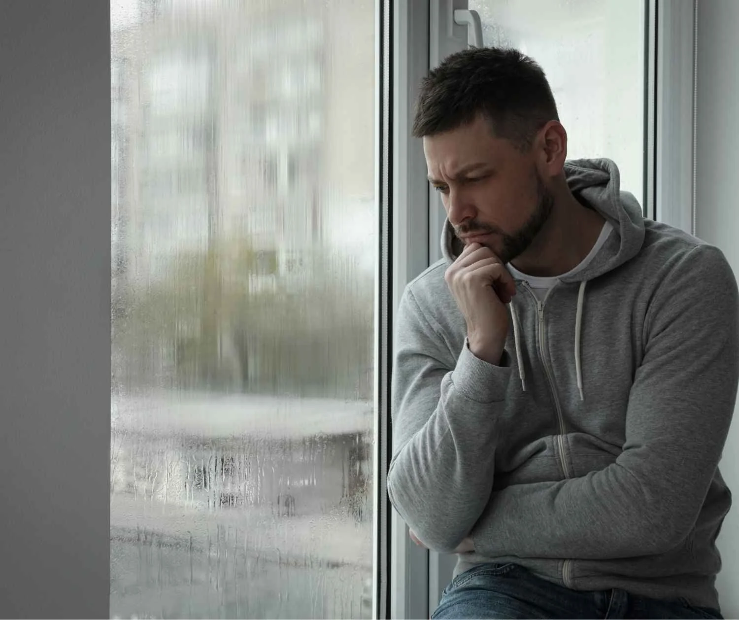Man sitting by a window at home, breathing slowly