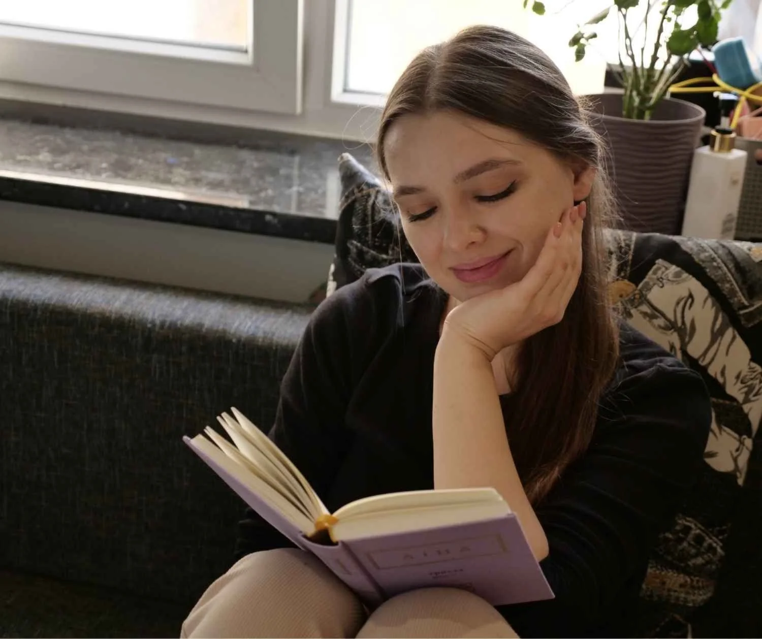 Girl reading book report at home