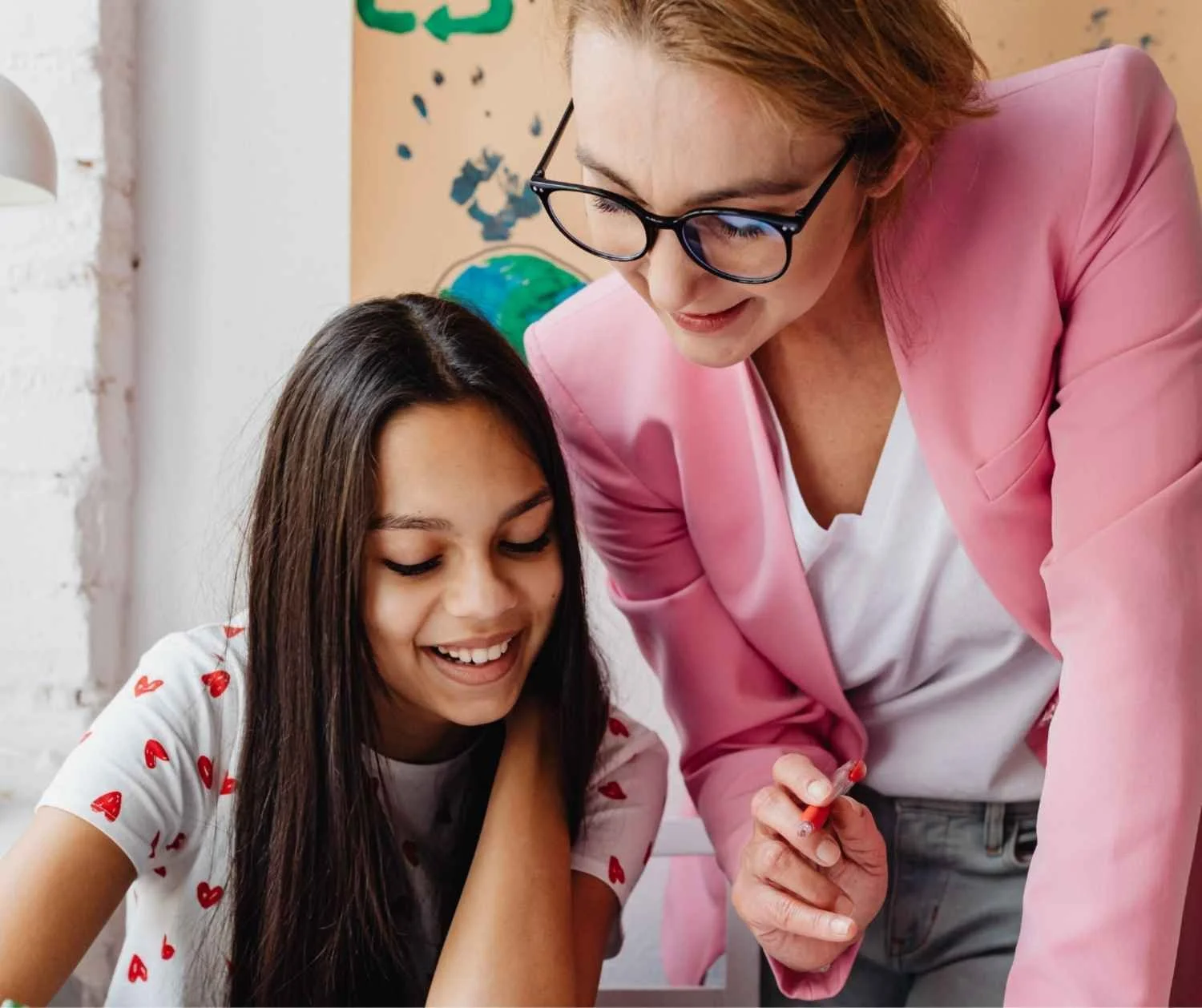 Teacher kneeling beside a student's desk to give a short instruction